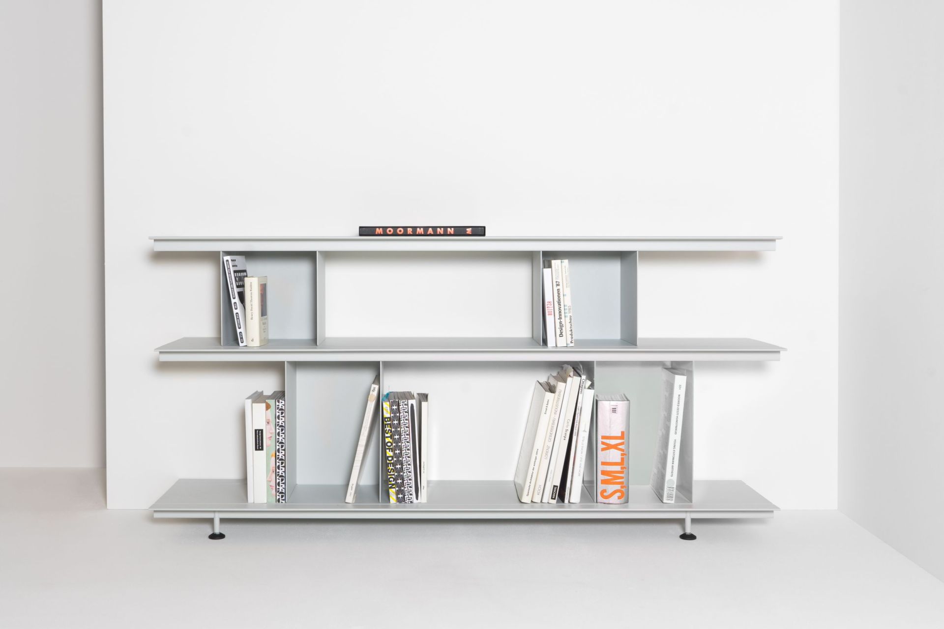 Helles, minimalistisches Zoll D Regal von Nils Holger Moormann mit Büchern vor weißem Hintergrund.