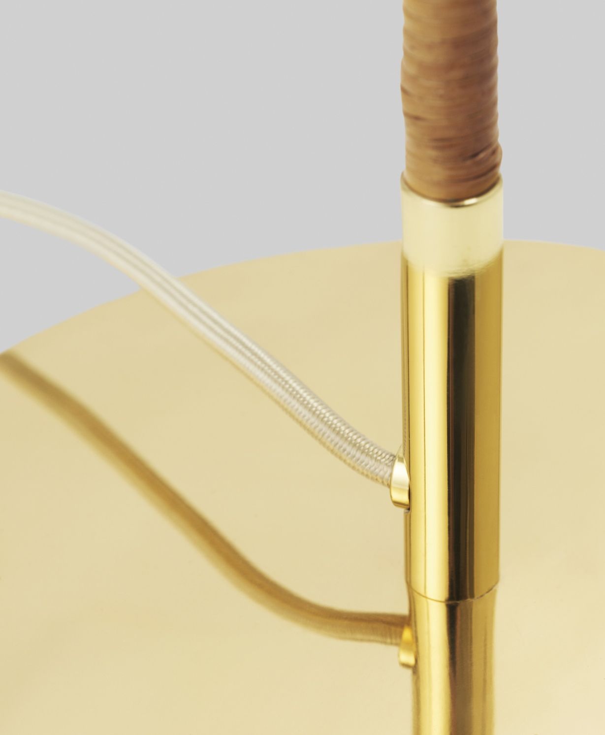 Detailaufnahme der Gubi 9602 Stehleuchte mit goldenem Fuß und Rattan-Elementen. Design-Stehlampe für stilvolle Innenräume.