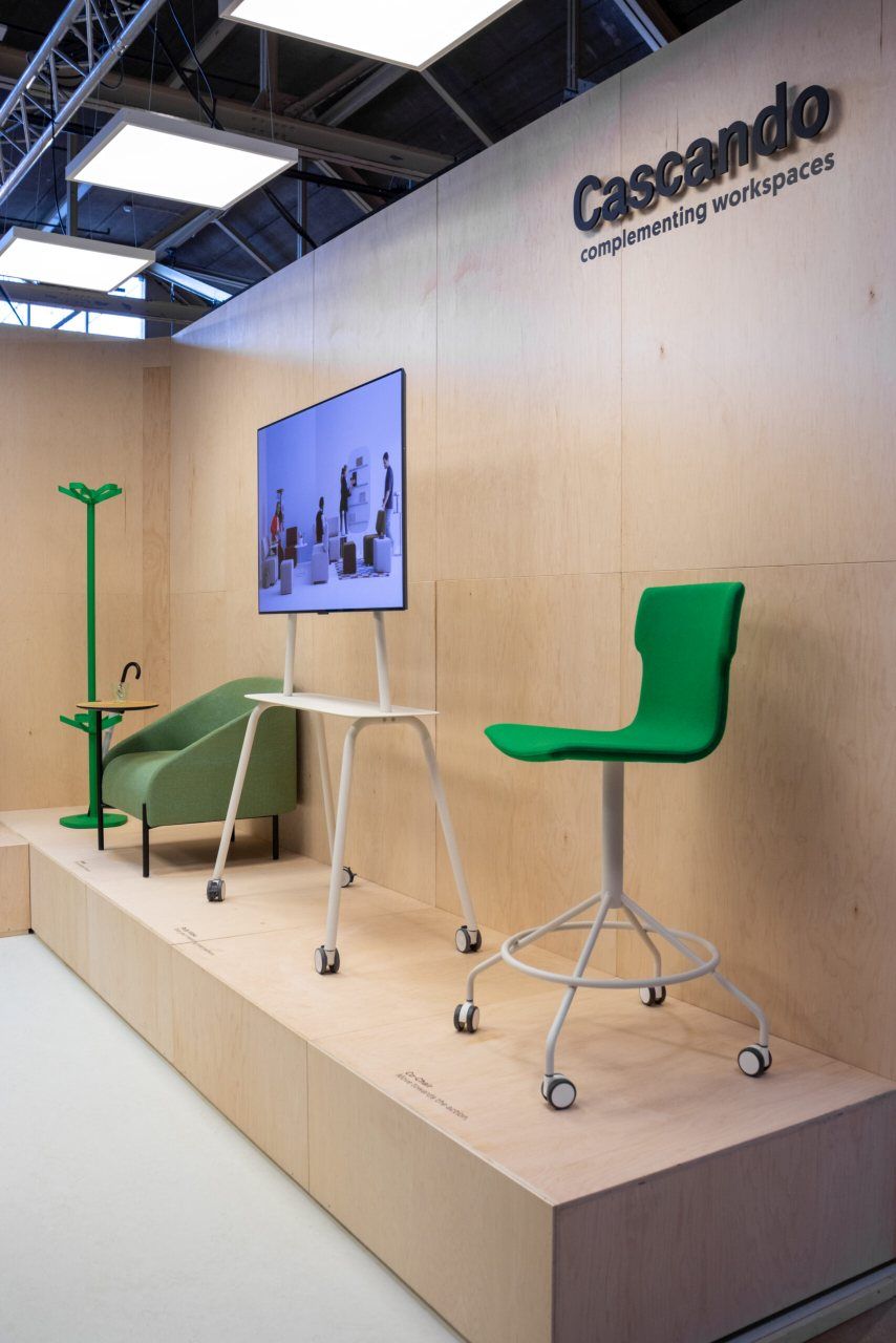 Cascando Co-Chair Bürodrehstuhl in Grün mit Rollen vor Holzwand, Teil einer Büromöbel-Ausstellung.