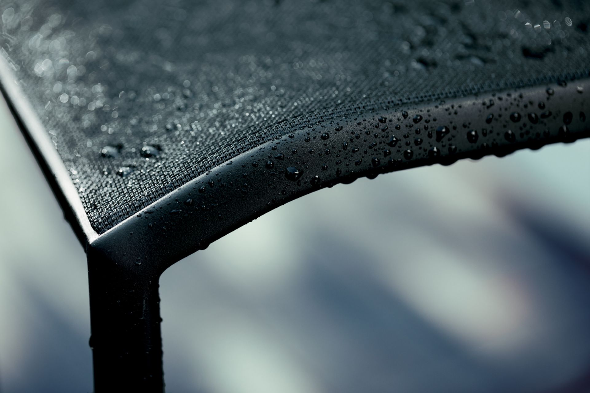 Detailaufnahme des schwarzen Cadiz Outdoor Stuhls von Fermob mit Wassertropfen auf der Sitzfläche.
