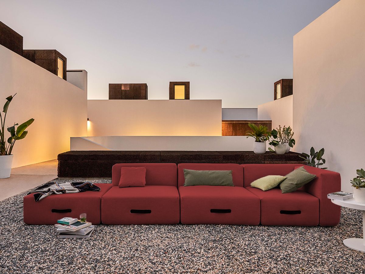 Rotes Conmoto Outdoor Sofa mit Kissen auf Kiesboden, moderne Gartenmöbel für Terrasse und Balkon.