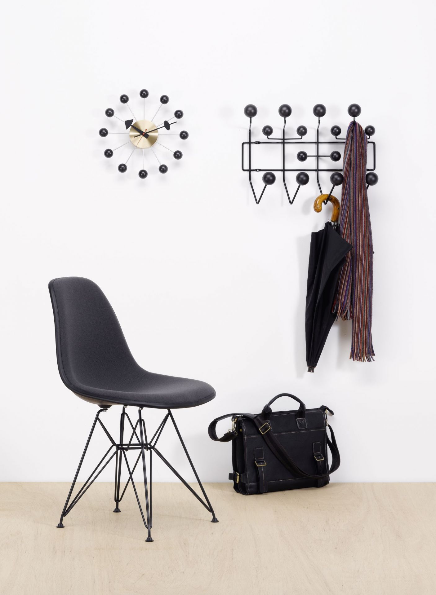 Eames Hang it all Garderobe Esche schwarz von Vitra mit Uhr, Stuhl und Tasche.