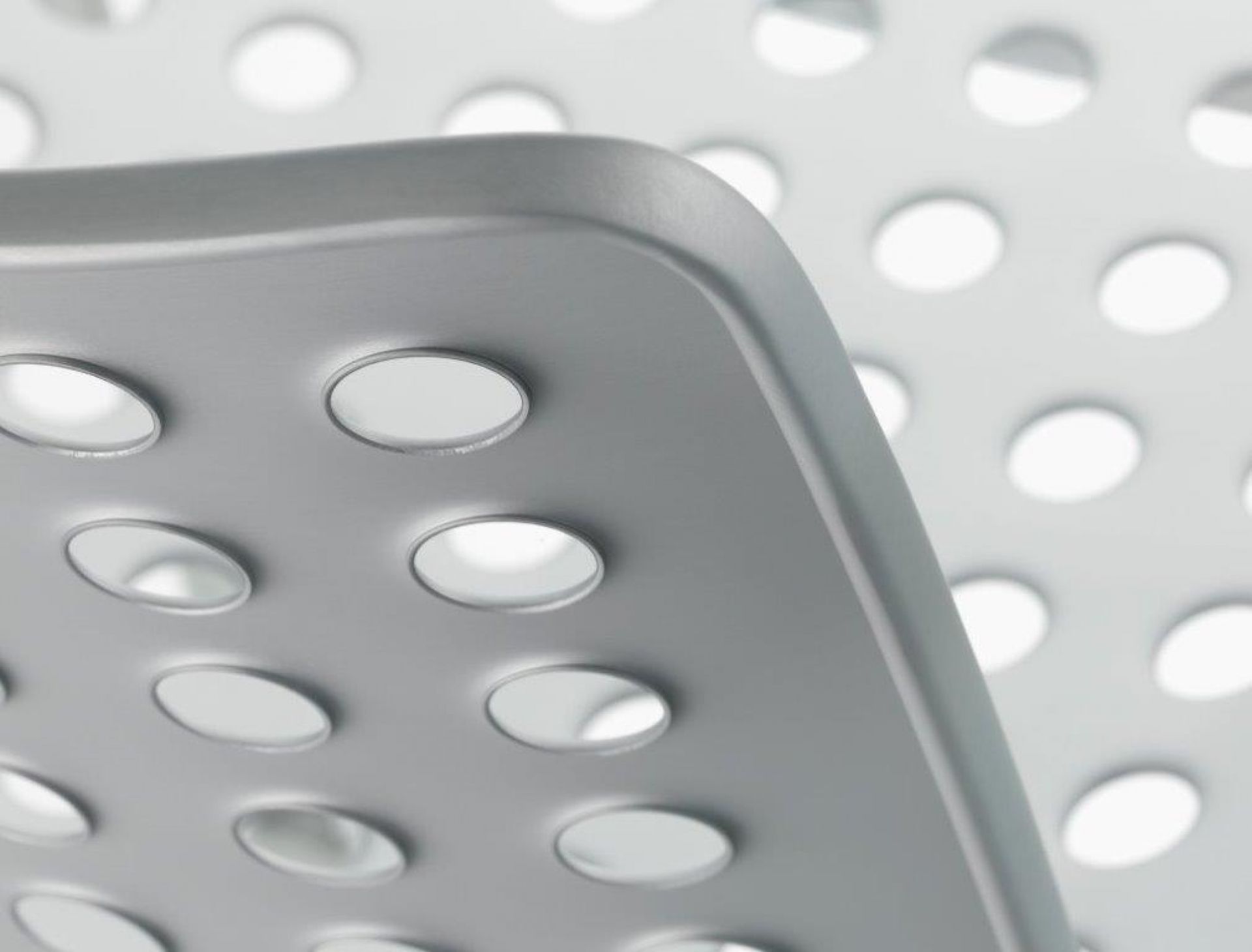 Detailaufnahme eines grauen Landi Stuhls von Vitra mit charakteristischer Lochmuster-Sitzfläche, modernes Design für Wohnen und Garten.