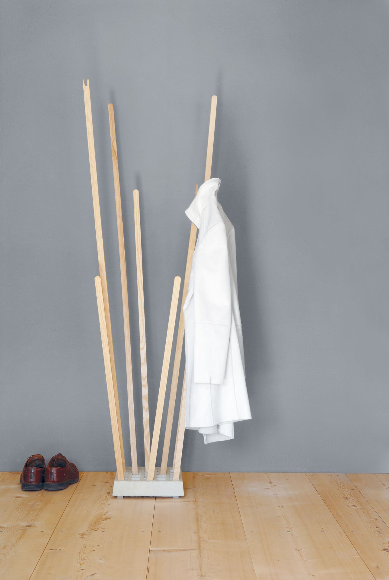 Pin Coat Garderobe von Moormann: Moderne Holzgarderobe mit weißem Mantel und braunen Schuhen. Designermöbel für Flur.
