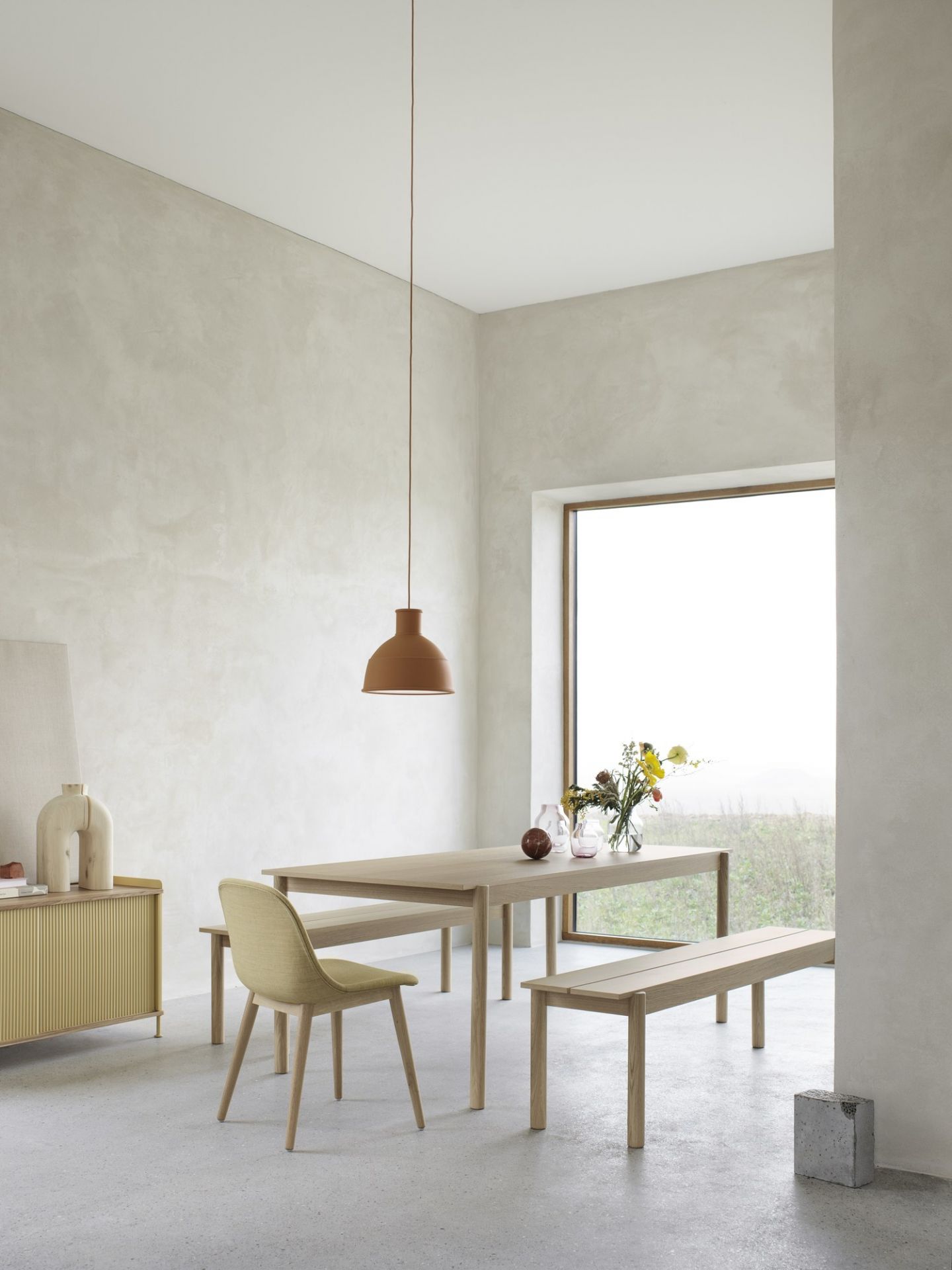 Helles Esszimmer mit Esstisch, Bänken, Stuhl und Enfold Sideboard von Muuto in gelb.