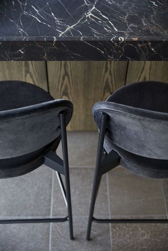 Detailaufnahme von zwei grauen Verpan Series 430 Barhockern mit schwarzem Gestell vor einer Marmor-Bar.