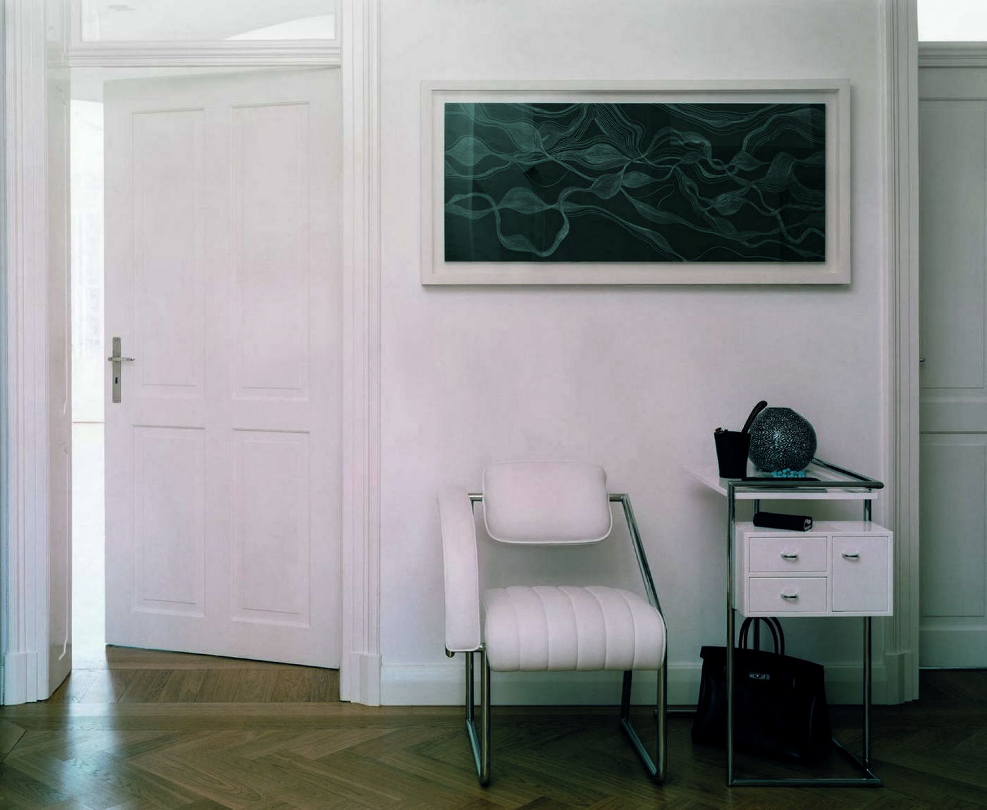 Weißer Non Conformist Sessel von ClassiCon mit Chromgestell in einem hellen Raum. Designermöbel für stilvolles Wohnen.