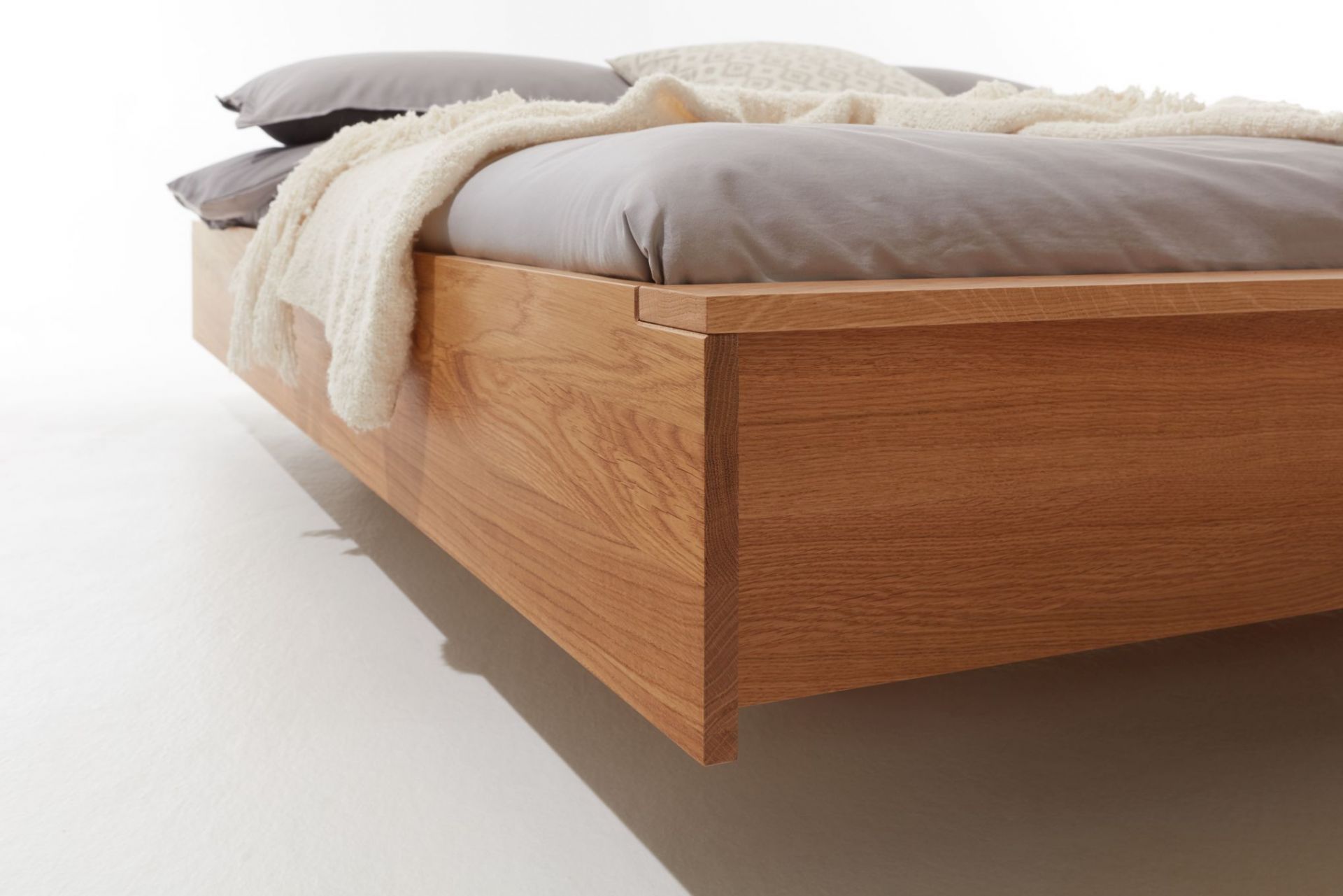 Detailaufnahme vom Flai Bett Eiche von Müller Möbelwerkstätten, modernes Design mit Bettwäsche und Kissen.