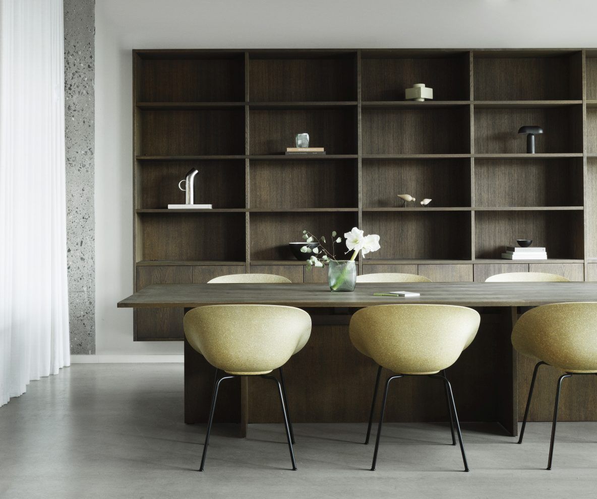 Gelbe Mat Armchair Stühle von Normann Copenhagen am Esstisch vor dunklem Holzregal.
