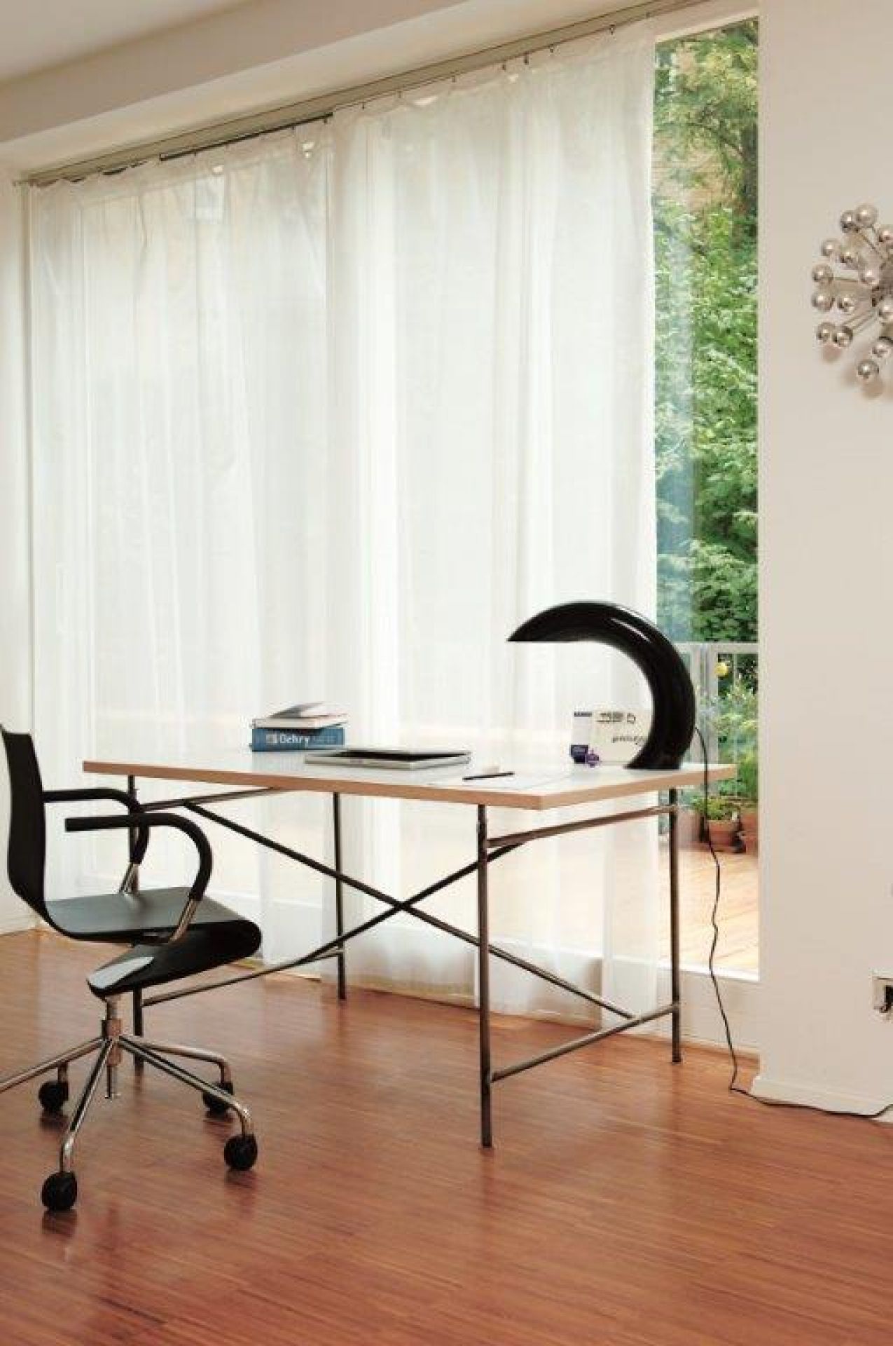 Eiermann Tischgestell mit schwarzen Kreuzstreben mittig, kombiniert mit Schreibtischstuhl und Lampe in modernem Arbeitszimmer.