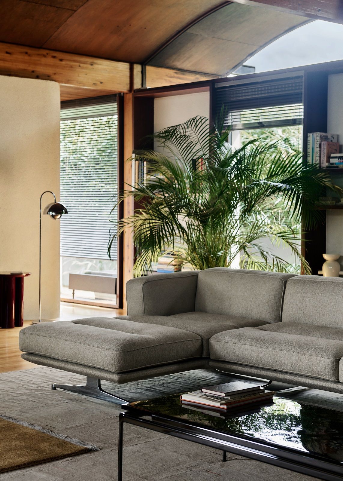 AndTradition Inland AV41 Sofa in grauem Stoffbezug mit Ottomane und schwarzem Couchtisch im Wohnzimmer.