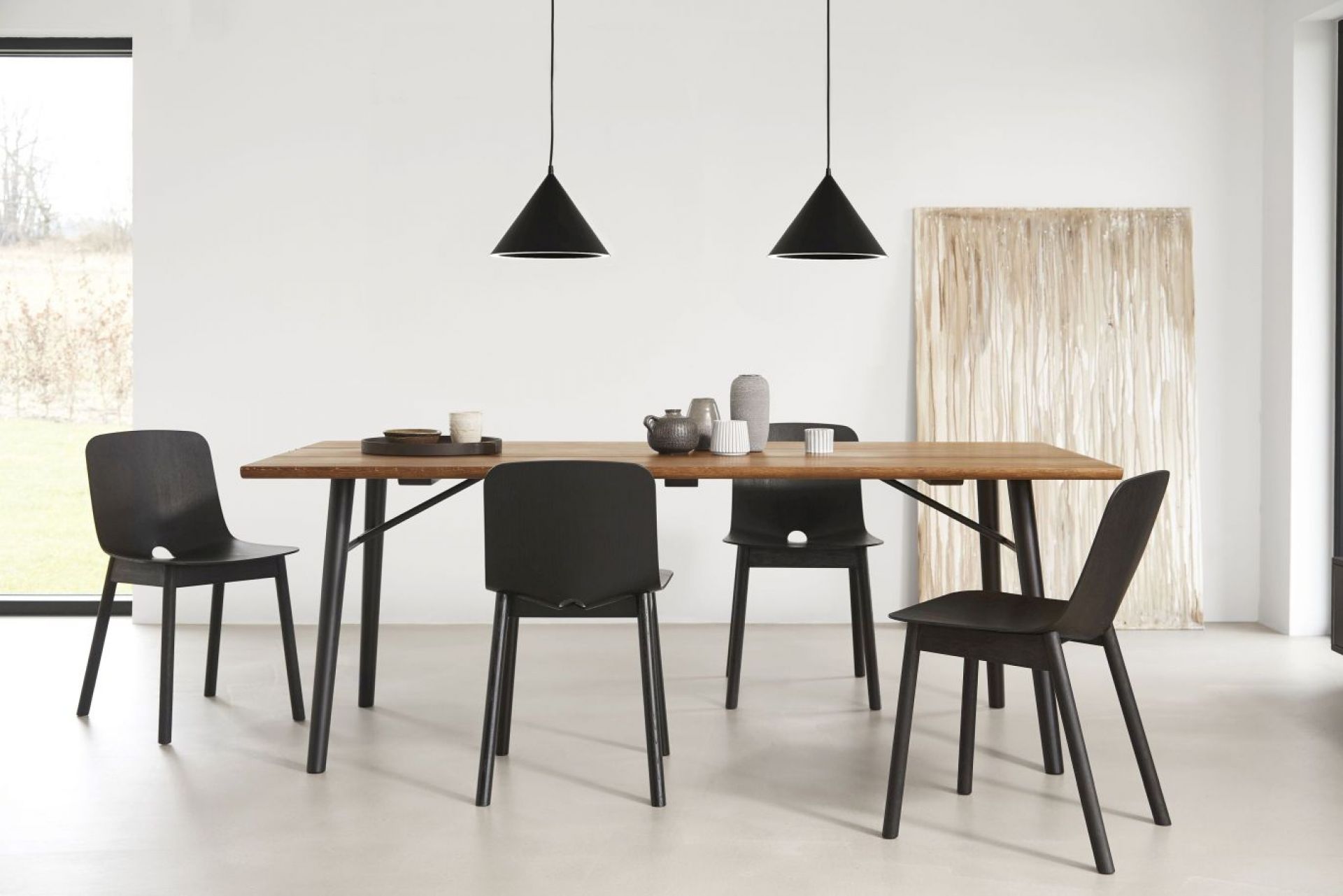 Esszimmer mit Holztisch und schwarzen Stühlen, beleuchtet von zwei schwarzen Annular Pendelleuchten.