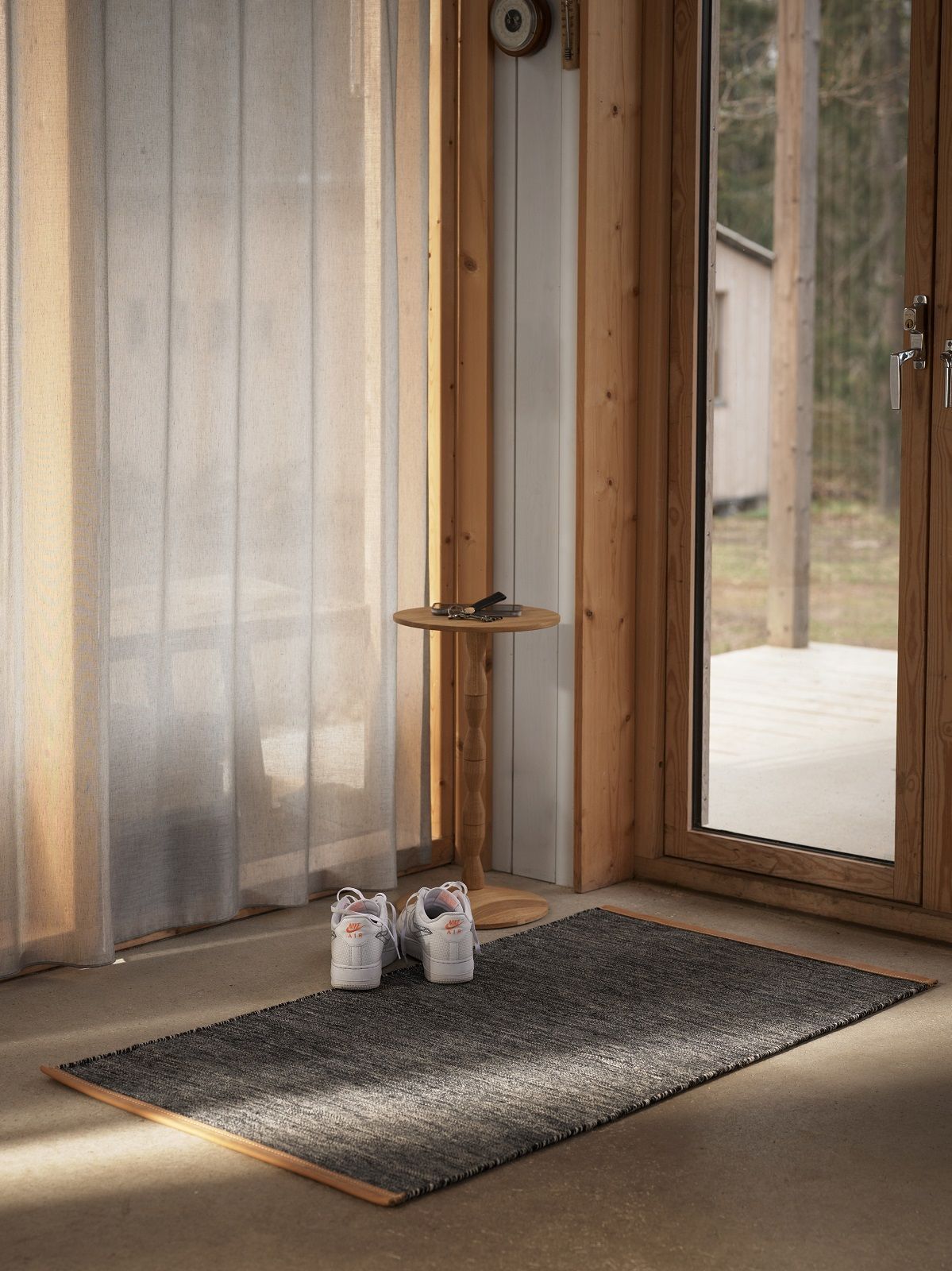 Grauer Björk Teppich von Design House Stockholm im Eingangsbereich mit Schuhen und Holzelementen.
