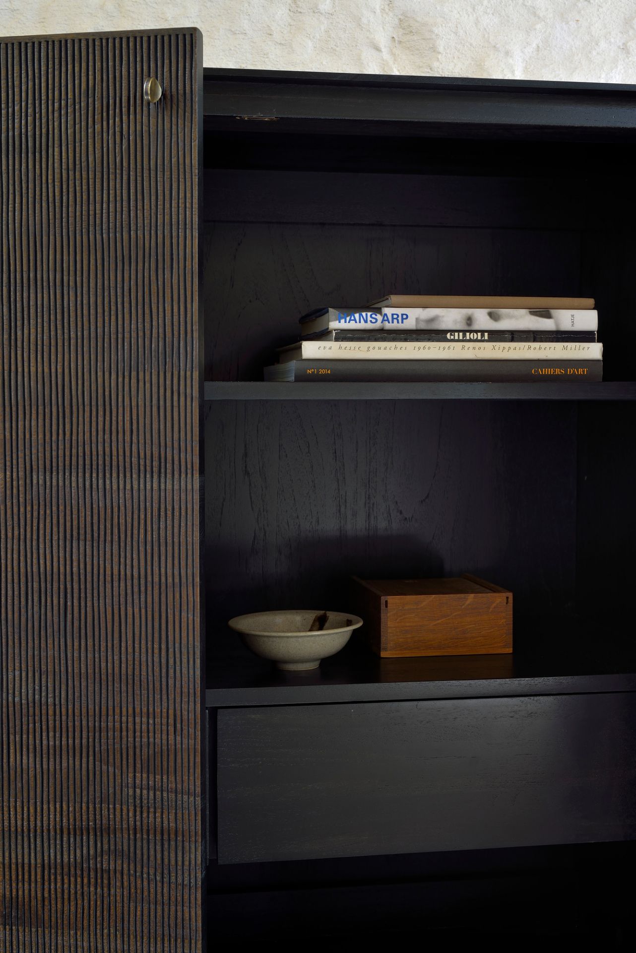 Ethnicraft Teak Grooves Schrank: Detailaufnahme des dunklen Holzschranks mit markanter, gerillter Schranktür und Innenleben.