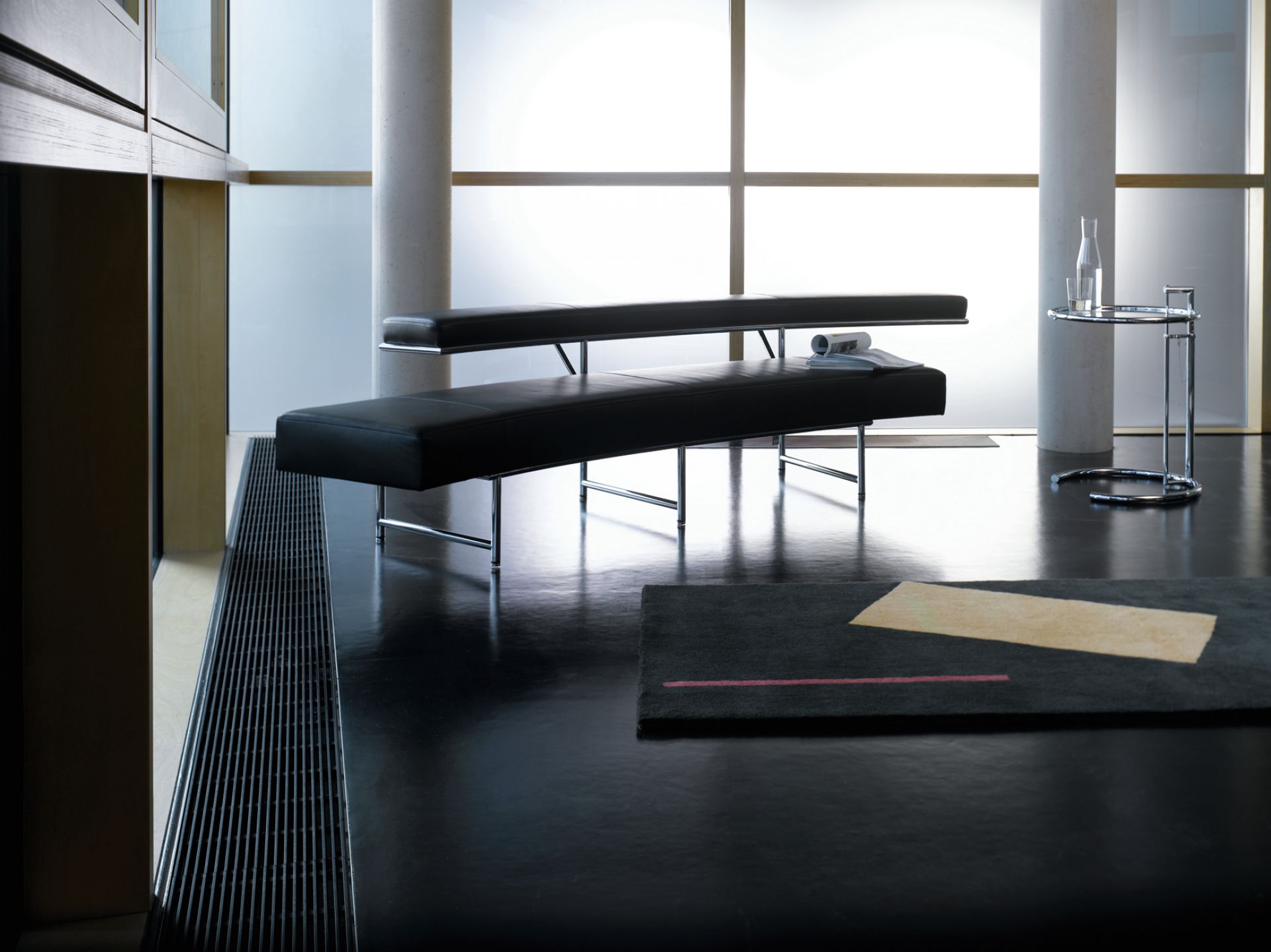ClassiCon E1027 Adjustable Table Beistelltisch im modernen Interieur mit schwarzen Bänken und minimalistischem Design.