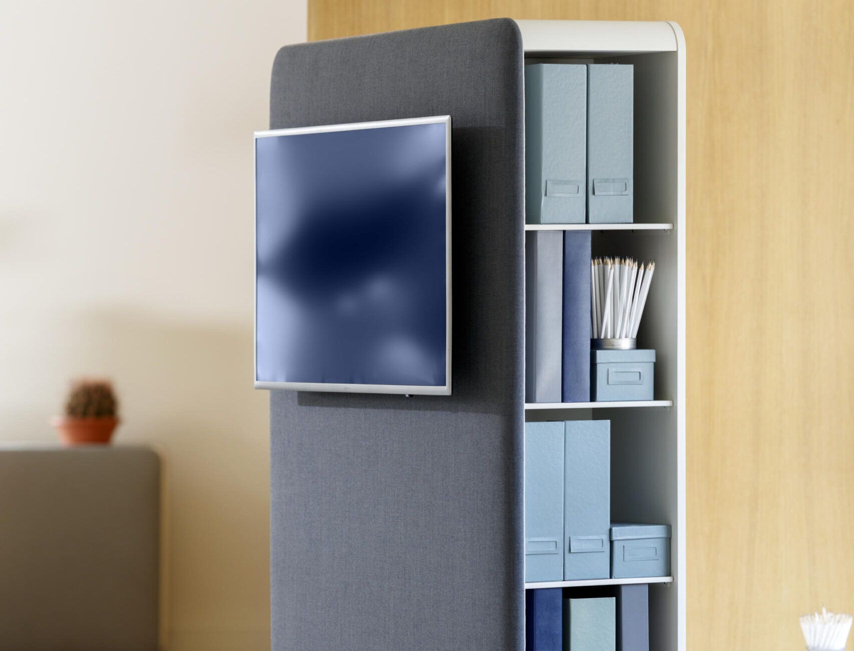 Cascando Pillow Space Akustik-Raumteiler mit montiertem Bildschirm und Regal mit Büroartikeln im modernen Büro.