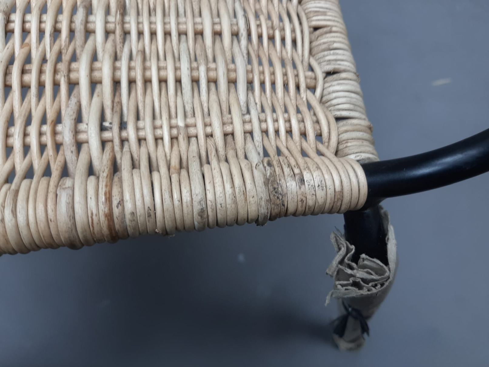 Detailaufnahme eines beschädigten Richard Lampert Stuhls TT 54 mit Rattan-Sitzfläche und defektem Fuß.
