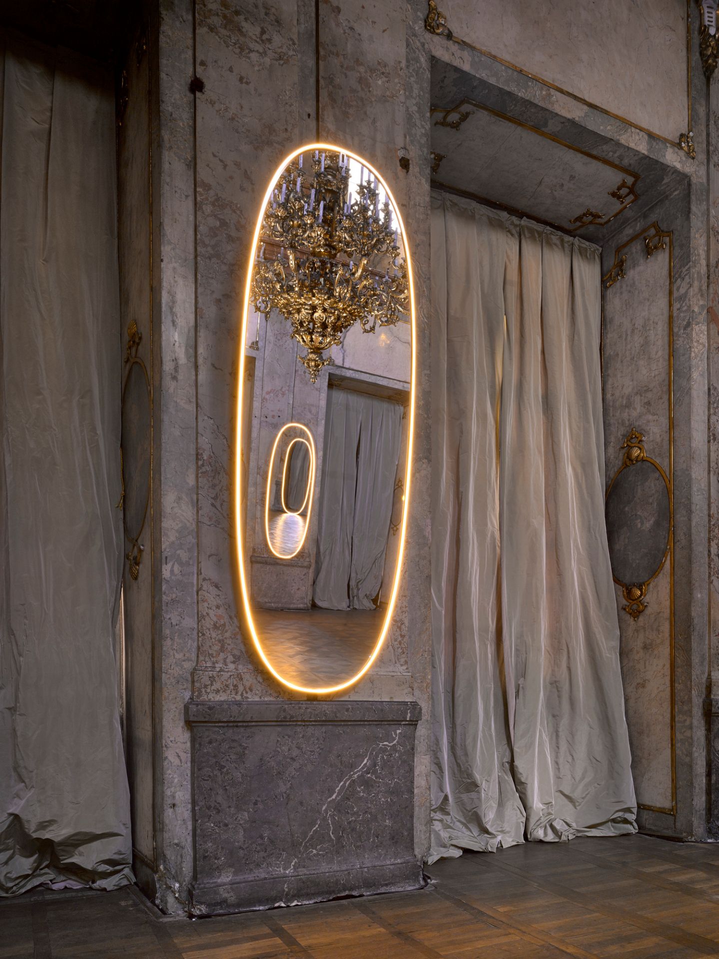 La Plus Belle Lichtspiegel von Flos: Ovaler Wandspiegel mit LED-Beleuchtung im luxuriösen Interieur mit Kronleuchter.