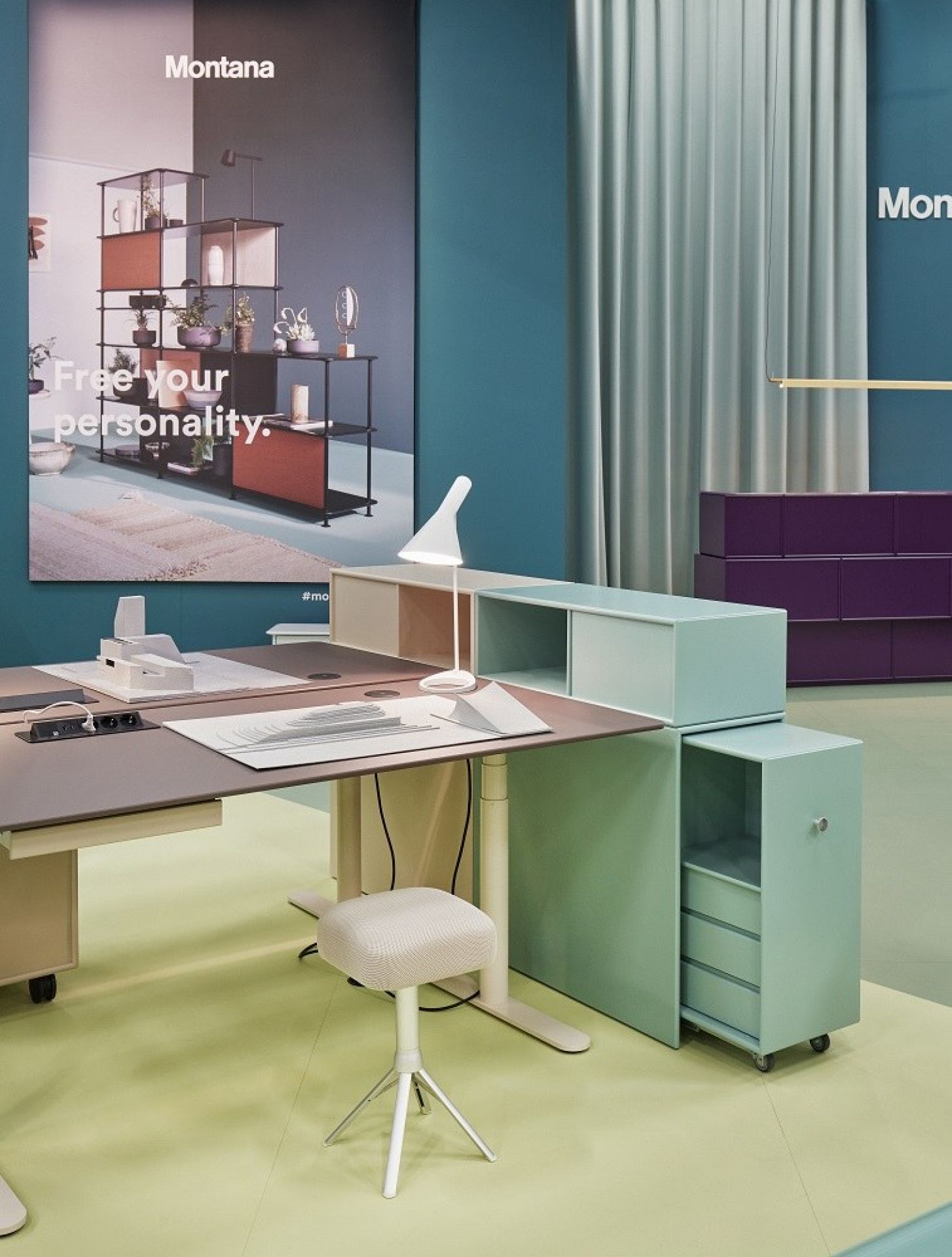 HiLow 2 elektrisch höhenverstellbarer Montana Schreibtisch mit Rollcontainer und Hocker in modernem Büro.