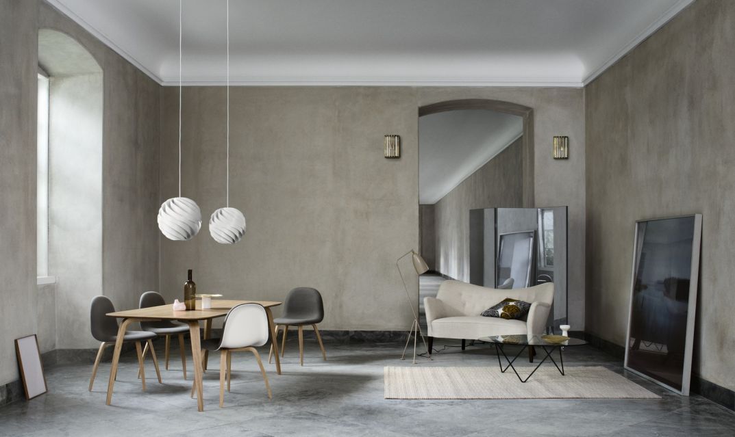 Wohnzimmer Interieur mit Gubi Couchtisch, Sofa, Esstisch und Pendelleuchten in minimalistischem Design.
