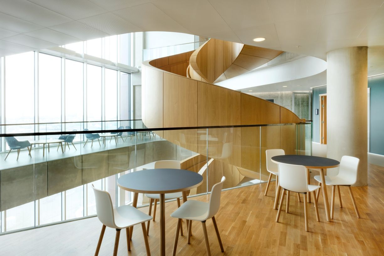 Heller Raum mit Holzboden, runden Tischen und weißen Hal RE Wood Stühlen von Vitra.