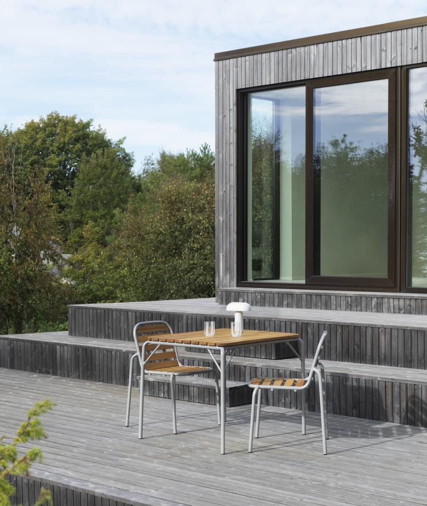 Vig Table 90x90 cm von Normann Copenhagen, quadratischer Outdoor Tisch mit zwei Stühlen auf Holzterrasse.