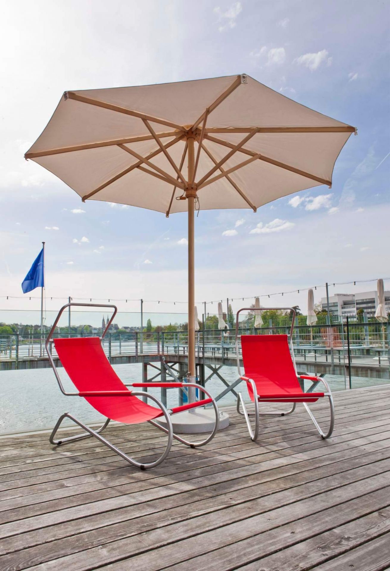 Zwei rote Lido Liegen auf Holzdeck mit Sonnenschirm, ideal für Garten, Terrasse und Pool.