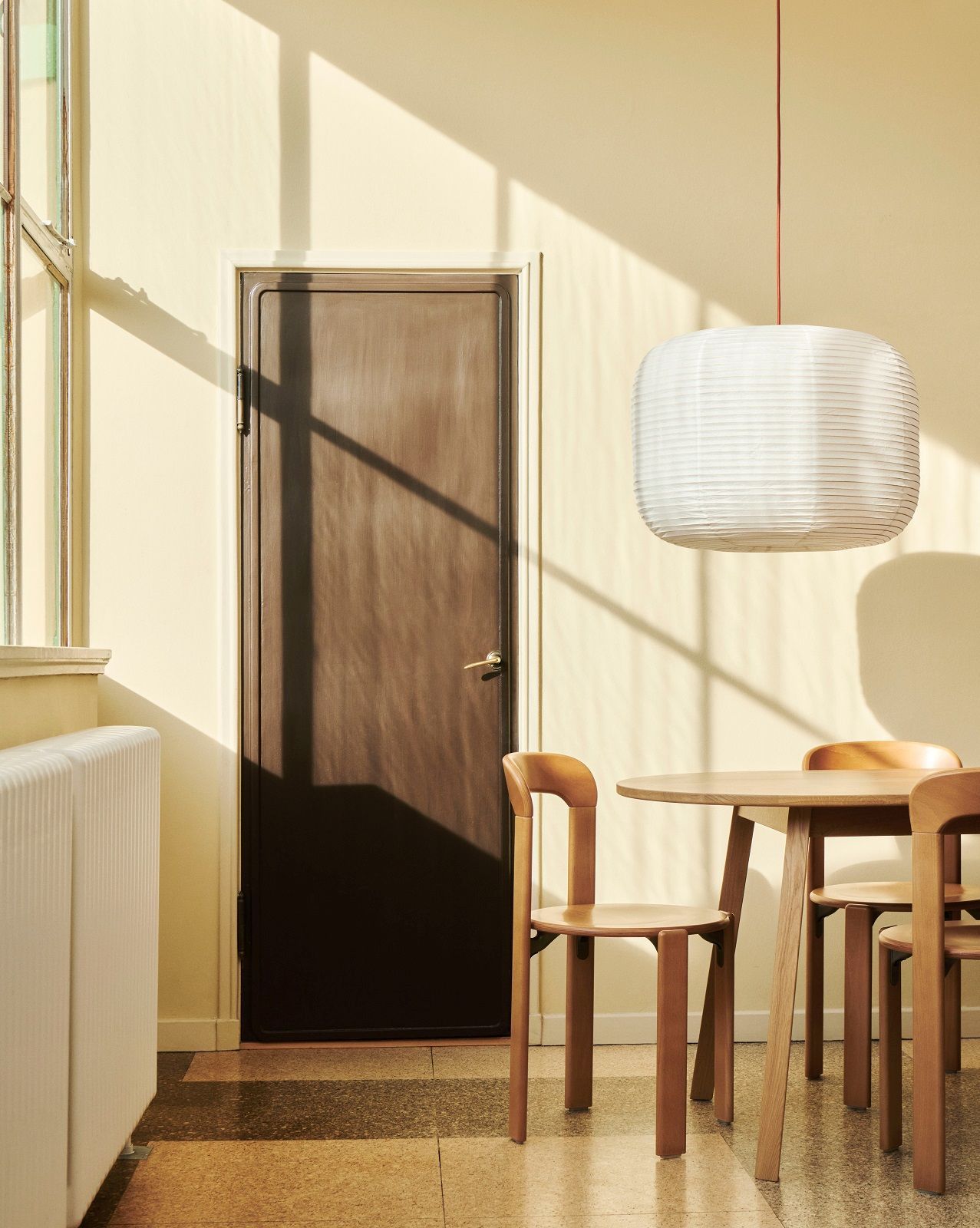 Heller Raum mit Hay Triangle Leg Esstisch aus Holz und passenden Stühlen unter einer Papierlampe.