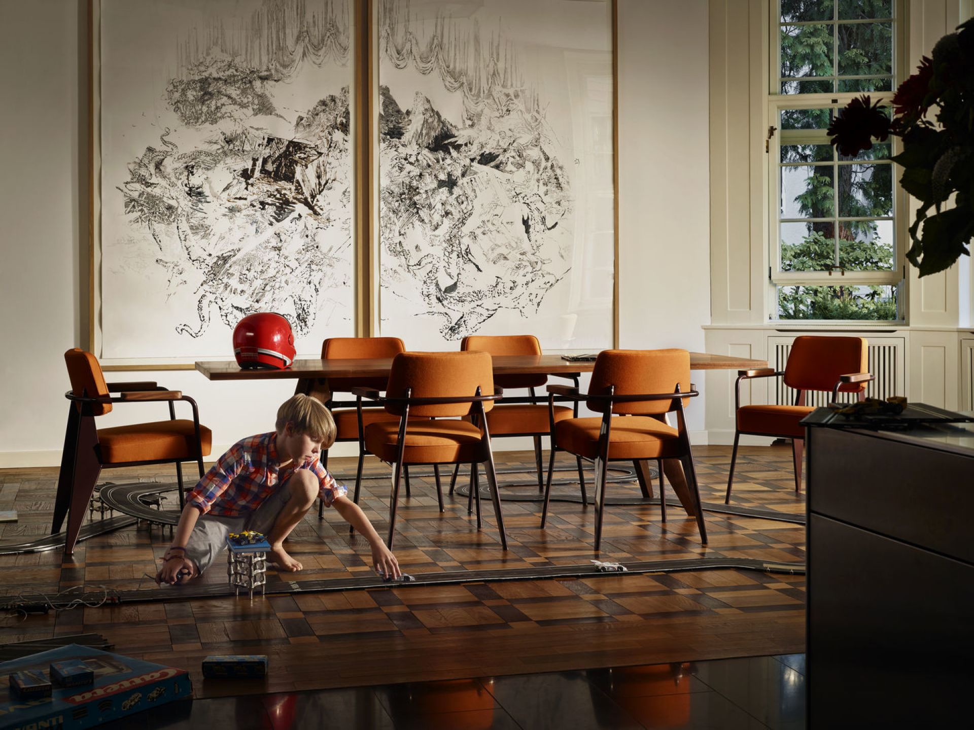 Oranger Fauteuil Direction Sessel von Vitra um einen Holztisch mit spielendem Kind im Wohnzimmer.