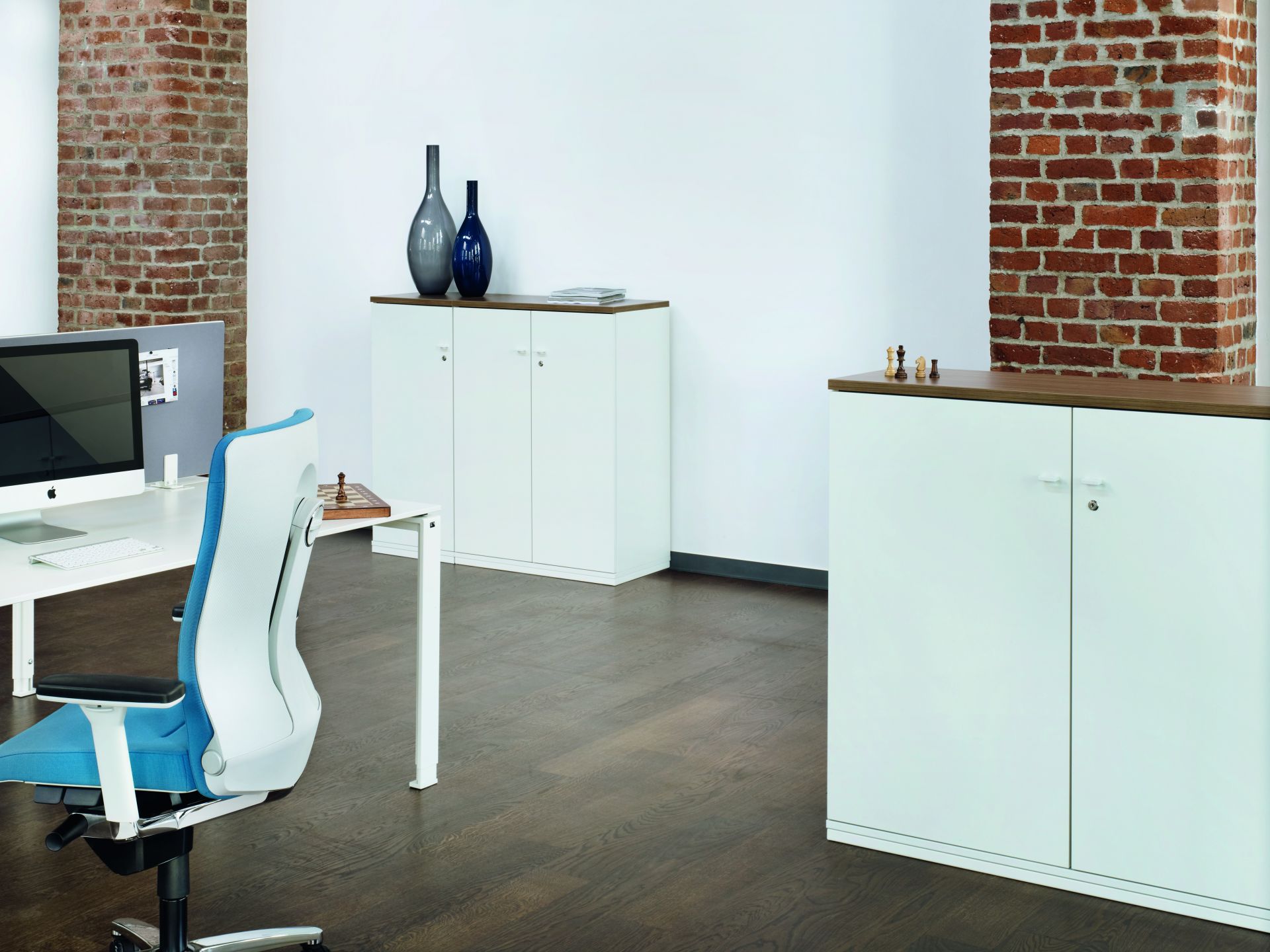 Büro mit weißen Acta Drehtürenschränken von König+Neurath, Holzboden und Büromöbeln. Stauraum für Bürobedarf.