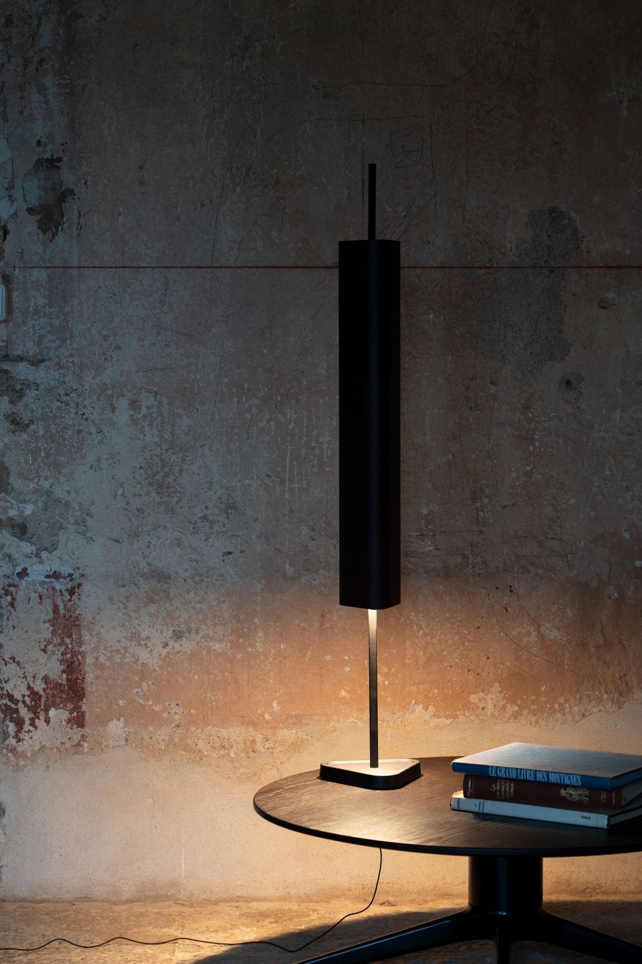 Emi Table Tischleuchte von Flos, modernes Design, tiefrote Farbe, warmes Licht, Bücher auf Tisch.