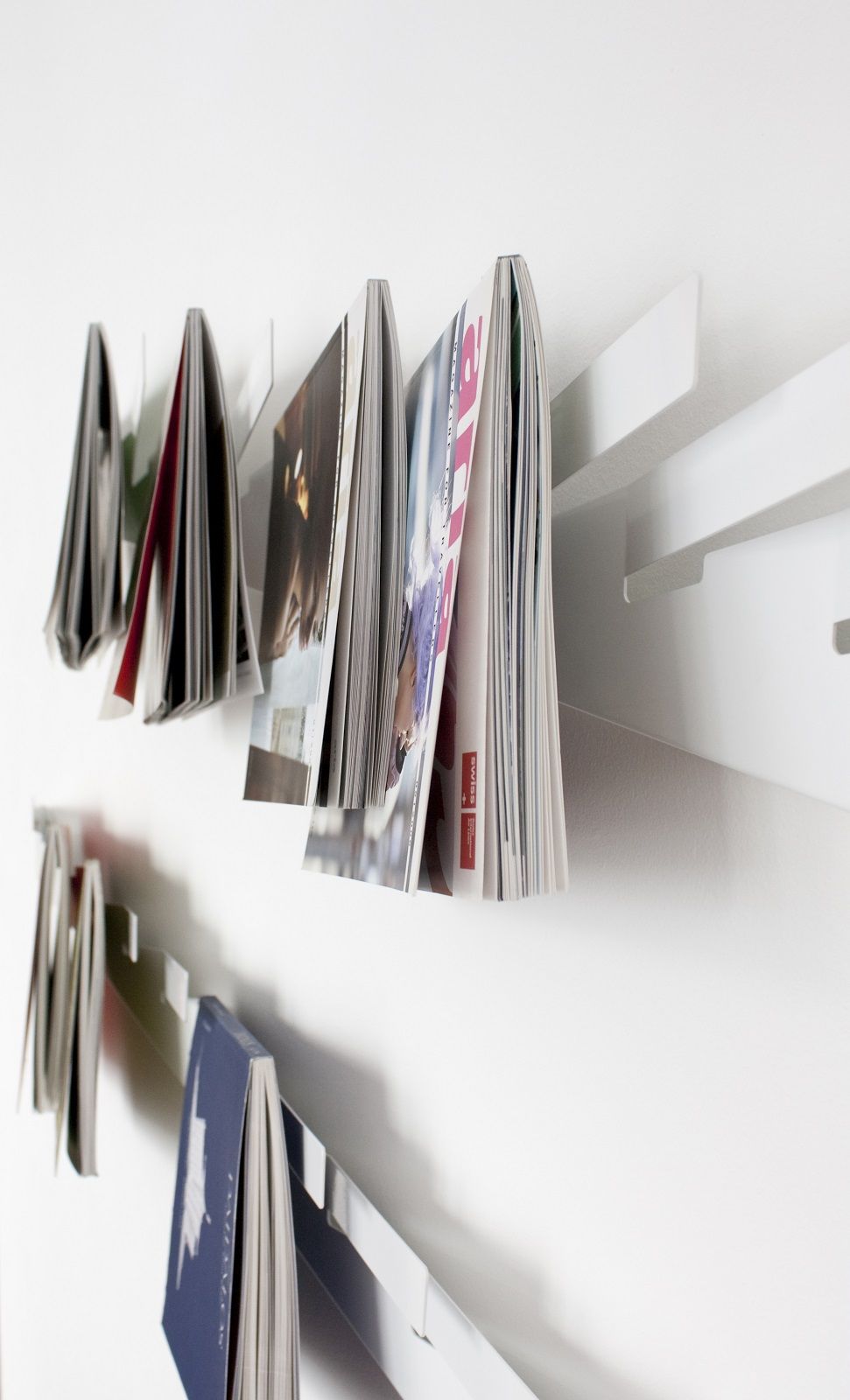 Weißes Wandregal mit Magazinen und Zeitschriften, modernes Design für Wohnzimmer oder Büro.