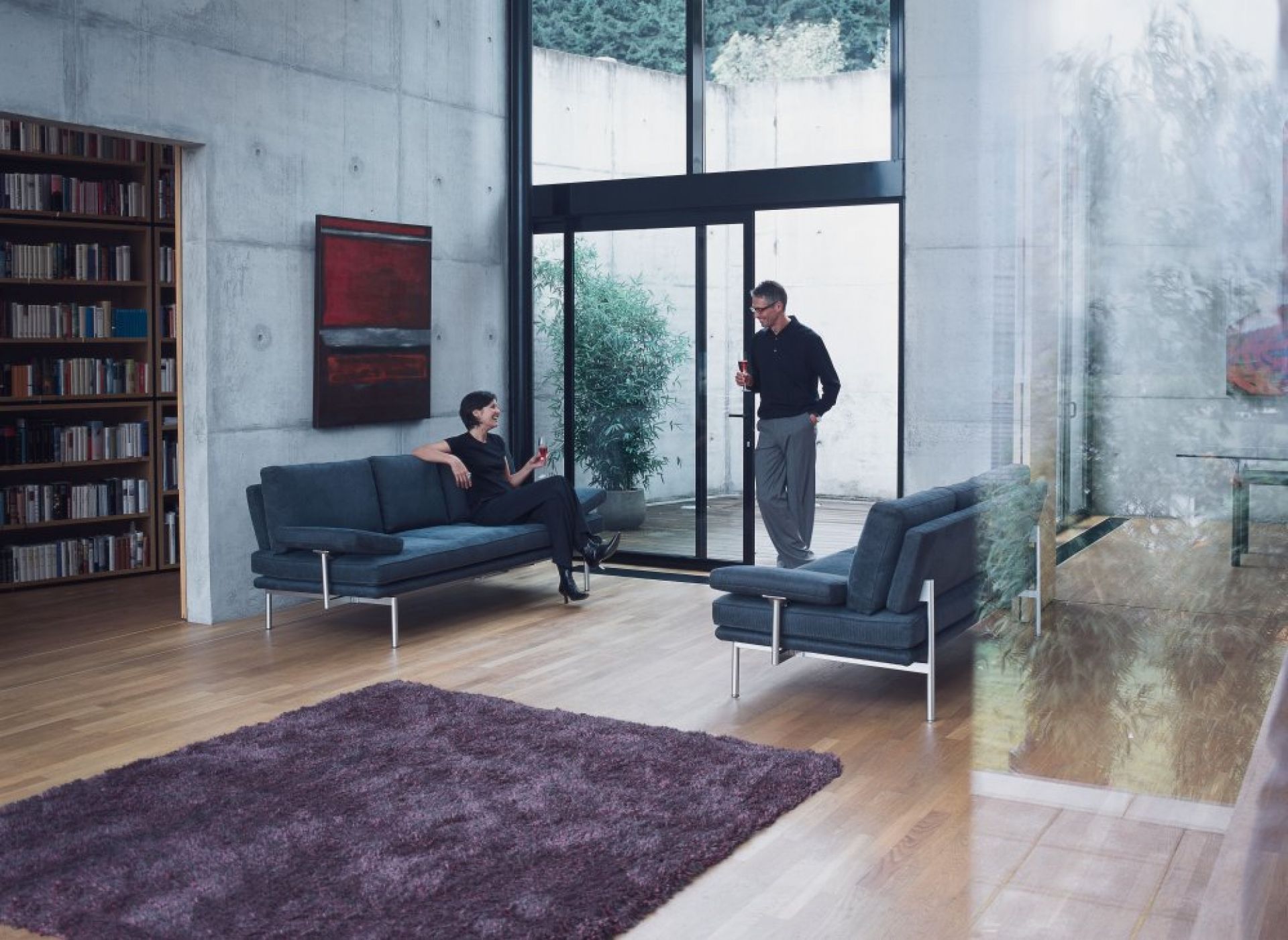 Modernes Wohnzimmer mit LIVING PLATFORM Sofa von Walter Knoll, blauer Polsterung und zwei Personen.