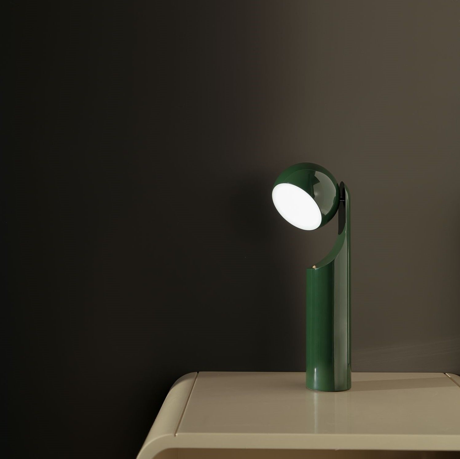 Grüne Mono Portable Akkuleuchte von house of home als Tischleuchte auf einem Nachttisch.