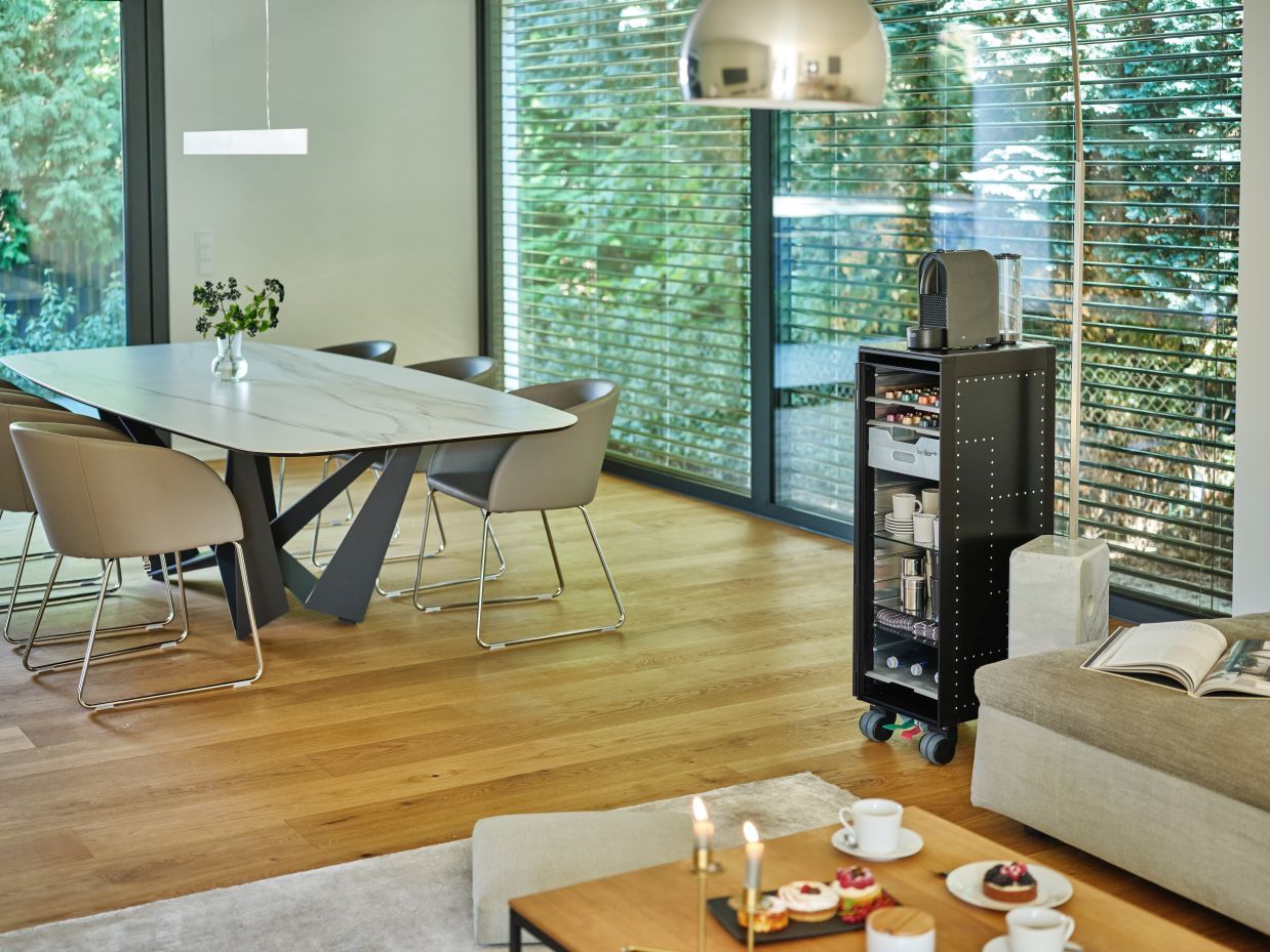 Schwarze Kaffee Equipment Bordbar mit Kaffeemaschine, Kapseln, Tassen und Gläsern im modernen Wohnzimmer.