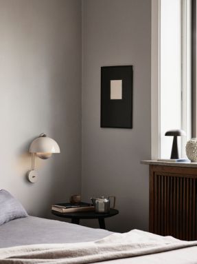 Flowerpot VP8 Wandleuchte von AndTradition in Beige an grauer Wand über einem Bett. Design-Wandlampe für Schlafzimmer.