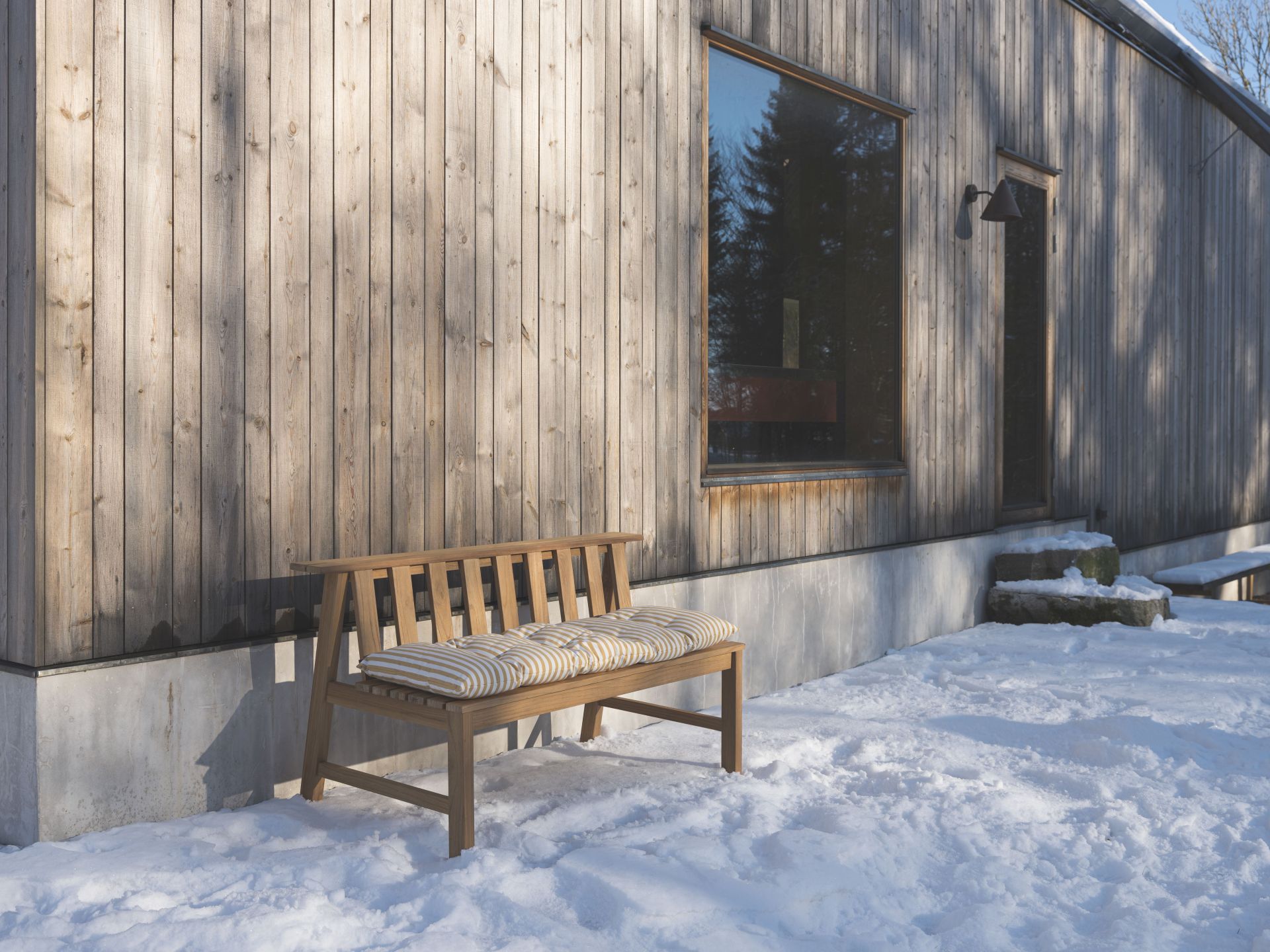 Cadence Bank Teak Gartenbank von Skagerak by Fritz Hansen mit gestreifter Auflage im Schnee.