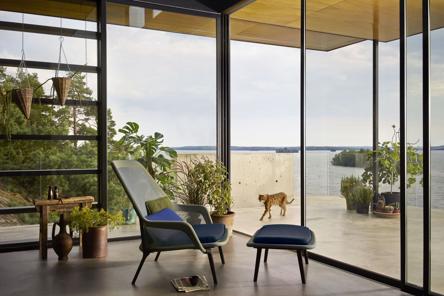 Vitra Slow Chair Sessel mit Ottoman in modernem Wohnraum mit Seeblick und Katze.