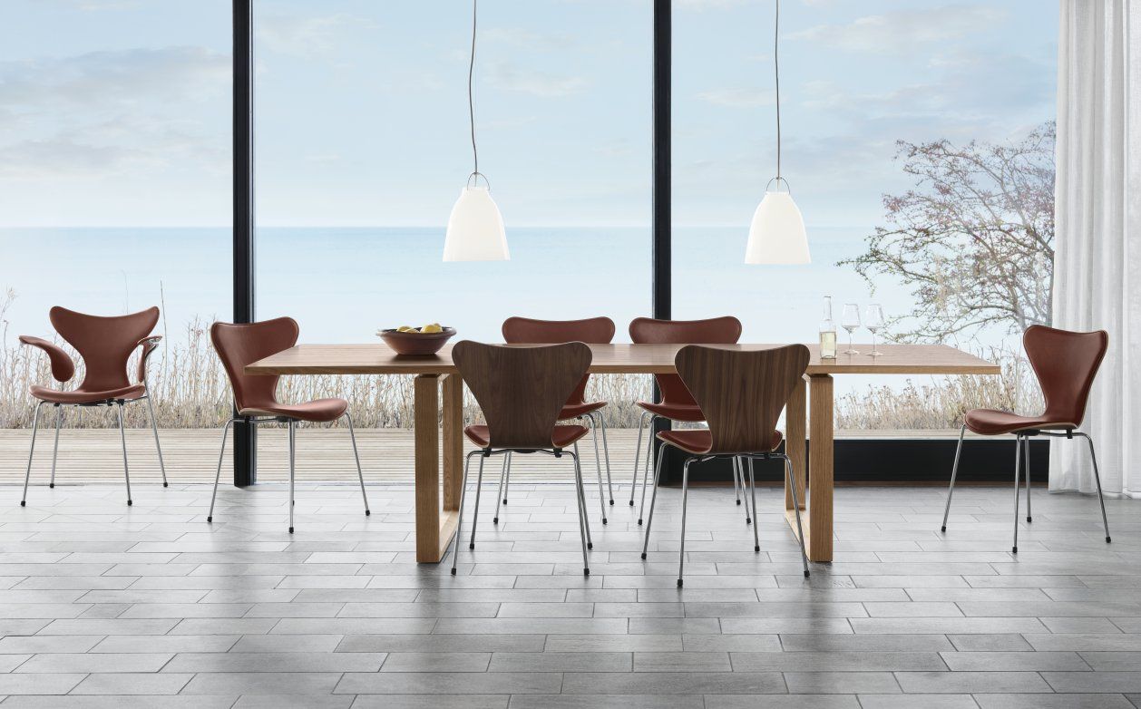 Esszimmer mit Holztisch, Stühlen und zwei weißen Caravaggio Pendelleuchten von Fritz Hansen über dem Tisch.
