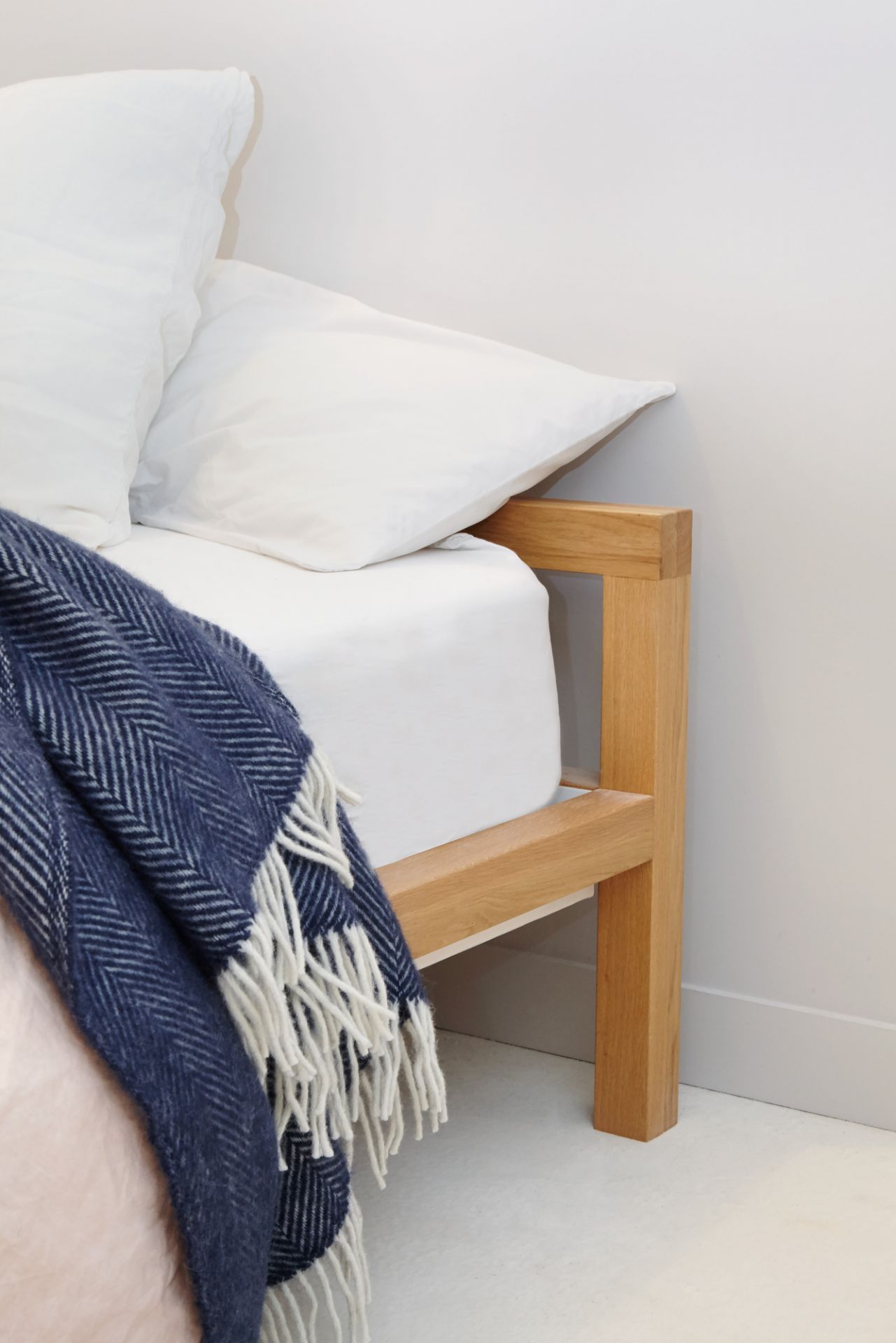 Detailaufnahme vom Hans Hansen Pure Bett aus Eiche (160x200 cm) mit blauer Decke.