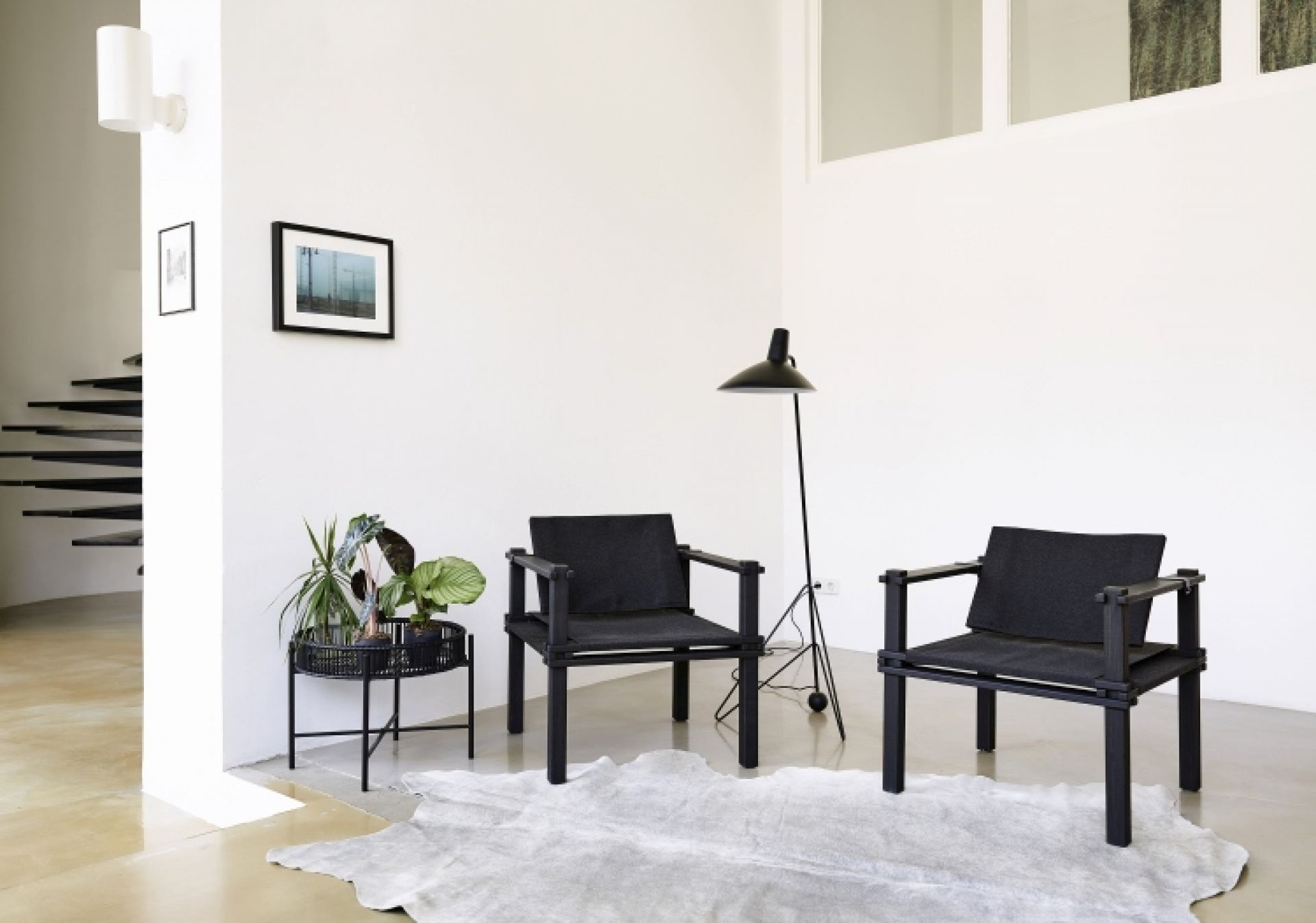 Zwei schwarze Farmer Sessel Outdoor Cor mit Kissen auf einem hellen Teppich in modernem Wohnzimmer.