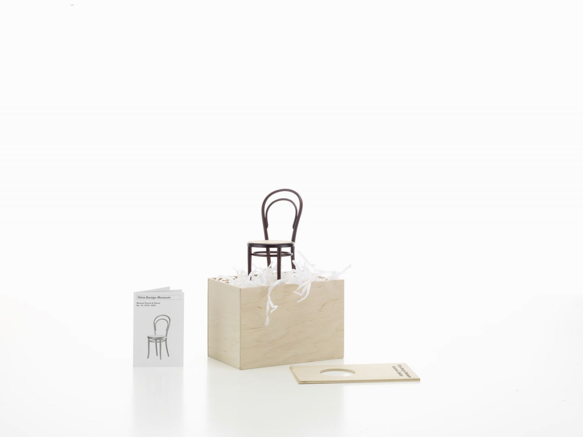 Miniatur Stuhl No. 14 von Vitra, Bugholzstuhl Designklassiker, auf hellem Holzwürfel mit Broschüre.
