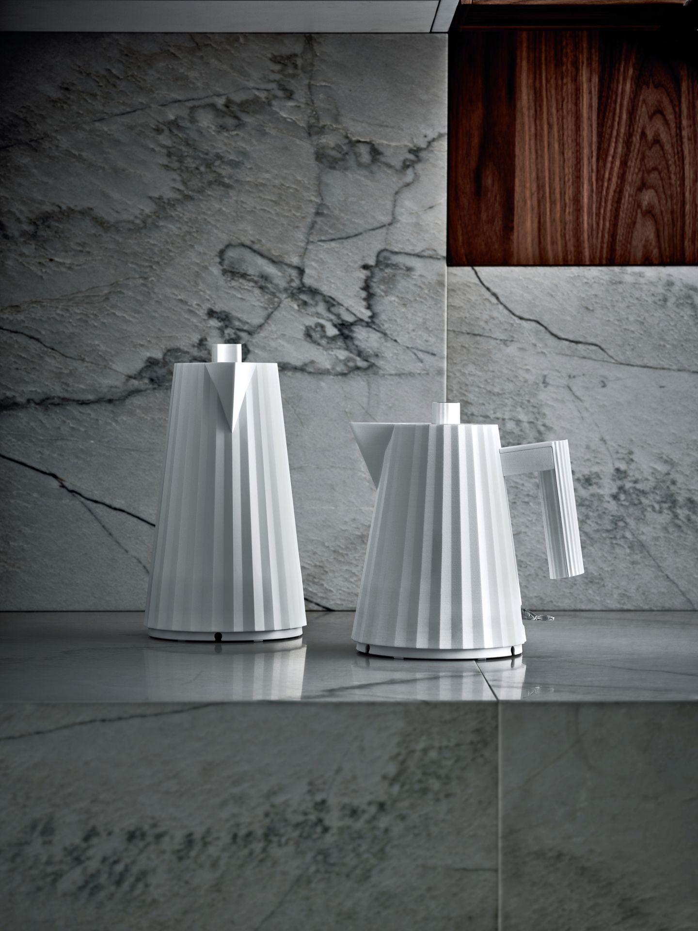 Zwei weiße Alessi Plissé Wasserkocher auf einer Marmoroberfläche, modernes Küchendesign.