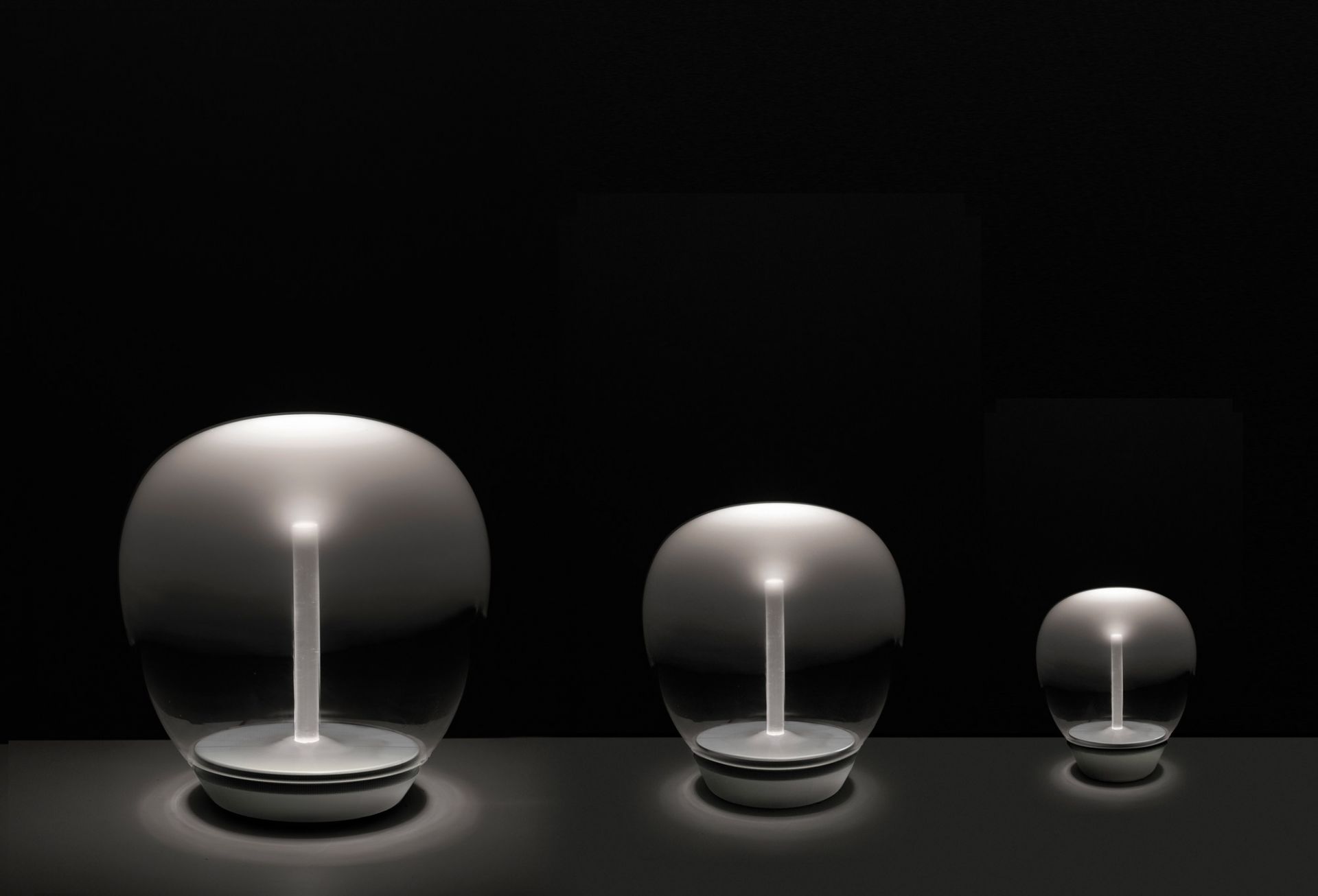 Drei Artemide Empatia Tischleuchten in verschiedenen Größen, modernes Design, stimmungsvolle Beleuchtung.