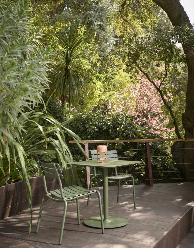 Alua Dining Chair von Houe, grüner Outdoor Stuhl und Tisch auf einer Holzterrasse im Garten.
