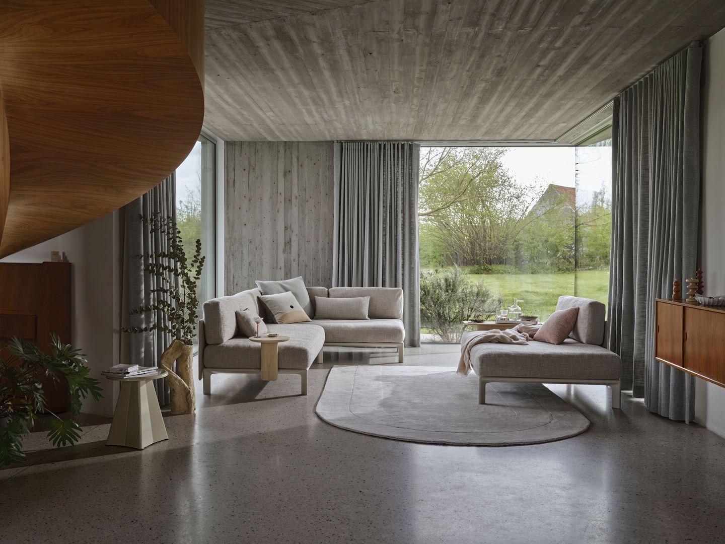 Helle Wohnzimmer-Szene mit modularem Sofa und Liege, dekoriert mit Vitra Cushions Kissen und Sofakissen.