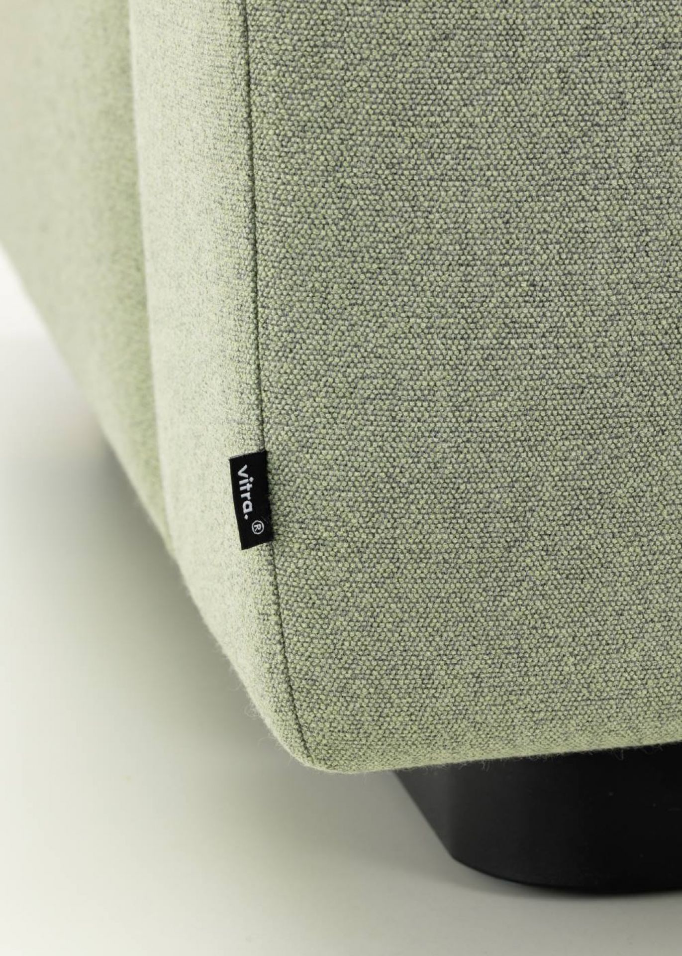 Detailaufnahme vom hellgrünen Vitra Sofa mit Stoffbezug und schwarzem Fuß, Label "vitra." sichtbar.