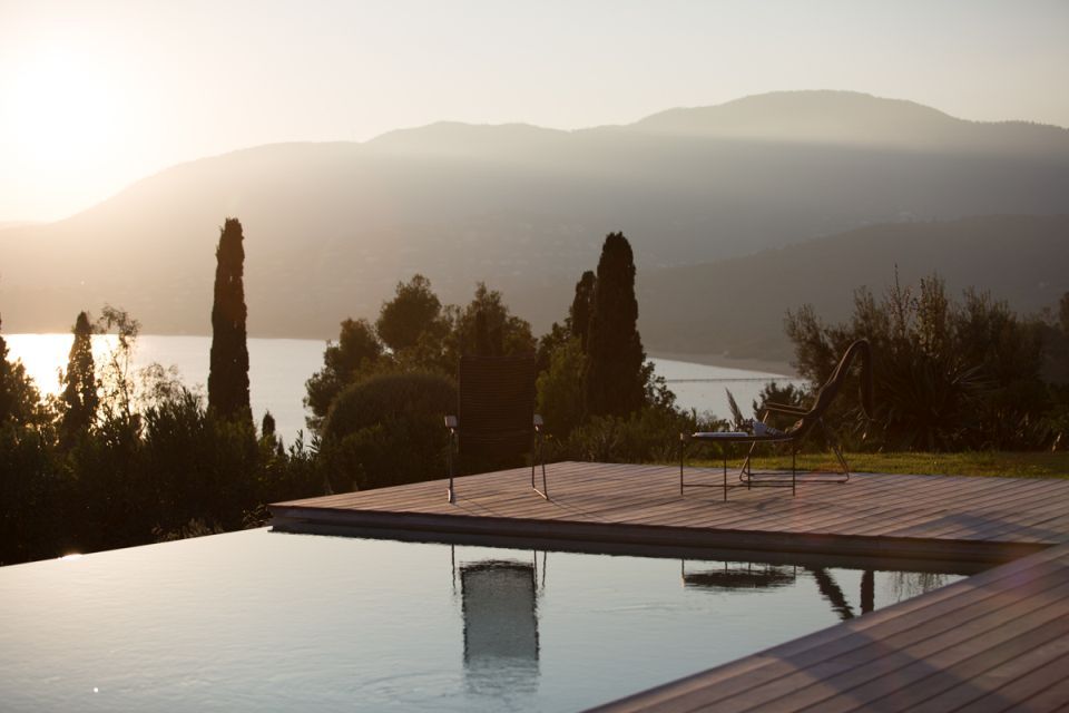 Click Lounge Chair von Houe auf Holzterrasse mit Pool und Meerblick. Outdoor Sessel.