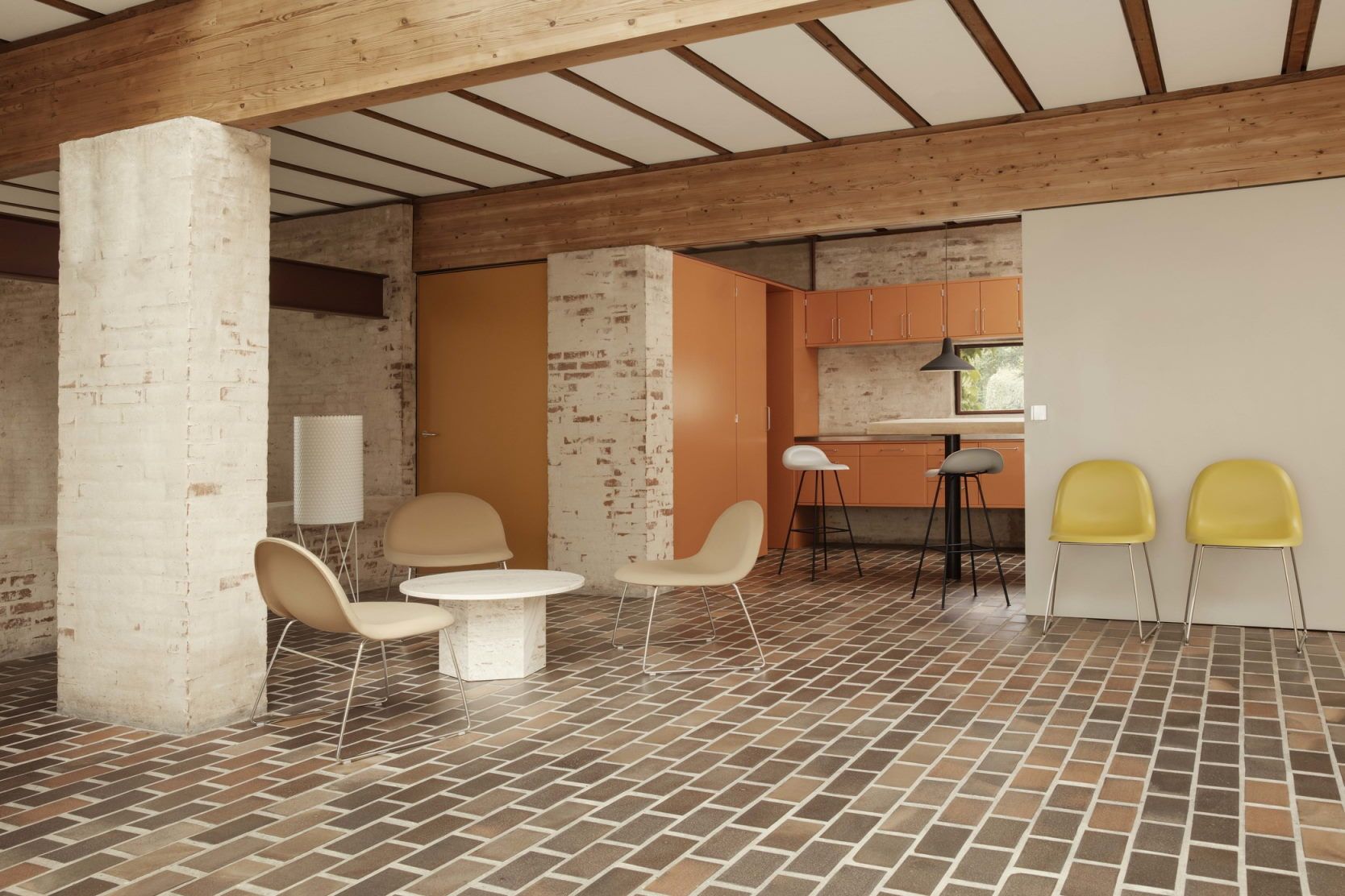 Innenraum mit Gubi Epic Couchtisch, Stühlen und Backsteinboden. Moderner Wohnraum mit Designermöbeln.