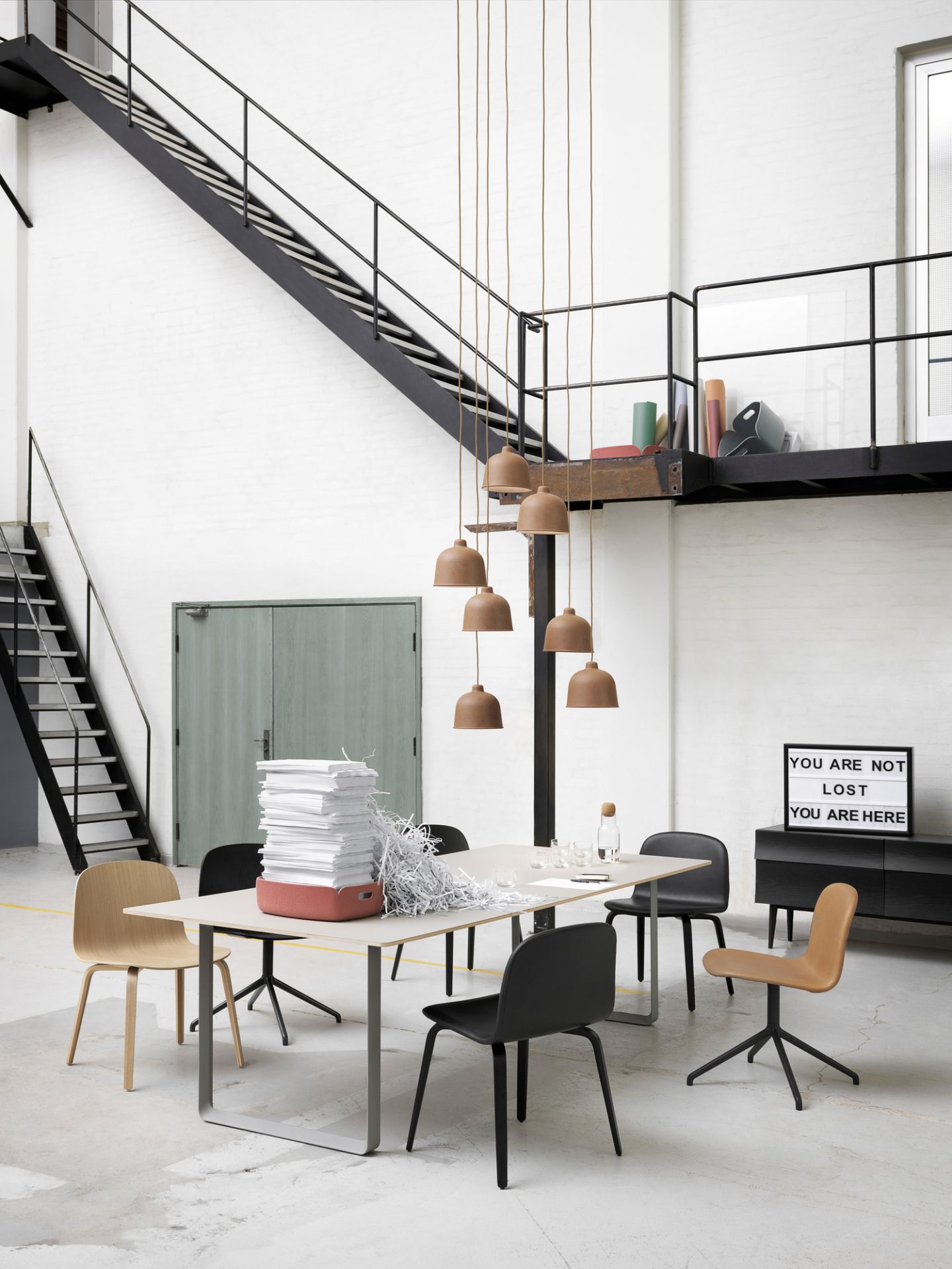 Muuto Base Table Round Tisch in hellem Büro mit Stühlen und Papierstapel.